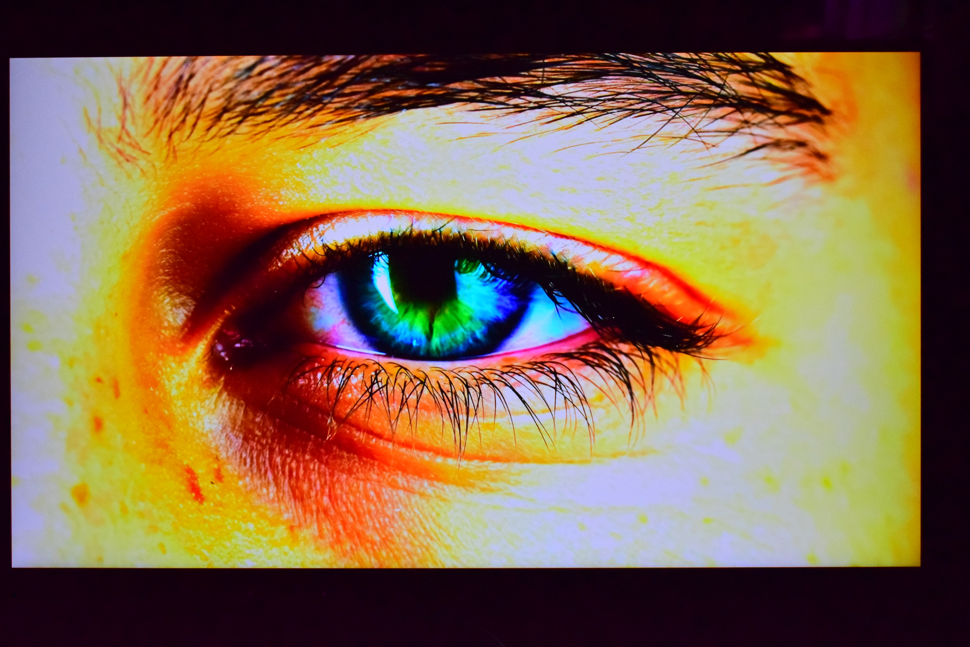 A close-up image of a human eye with a vibrant, multicolored iris, featuring shades of green, blue, and yellow.