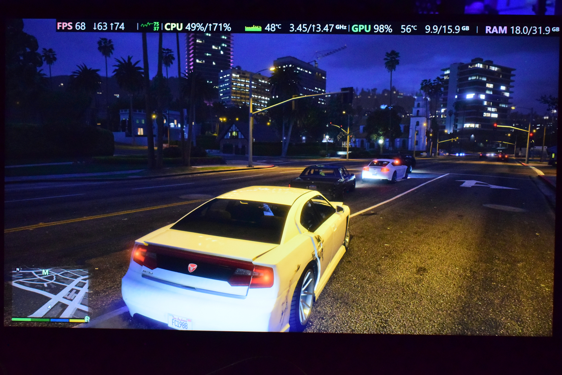 A car in Grand Theft Auto V driving through a city at night, displaying performance stats: 'FPS 68,' 'CPU 49%/171%,' and 'GPU 98%'.