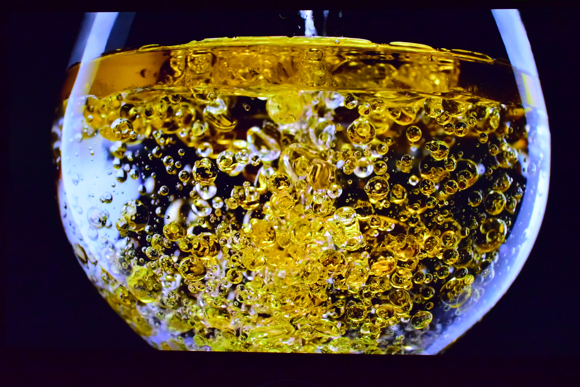 A close-up of carbonated bubbles rising in a glass of amber liquid.