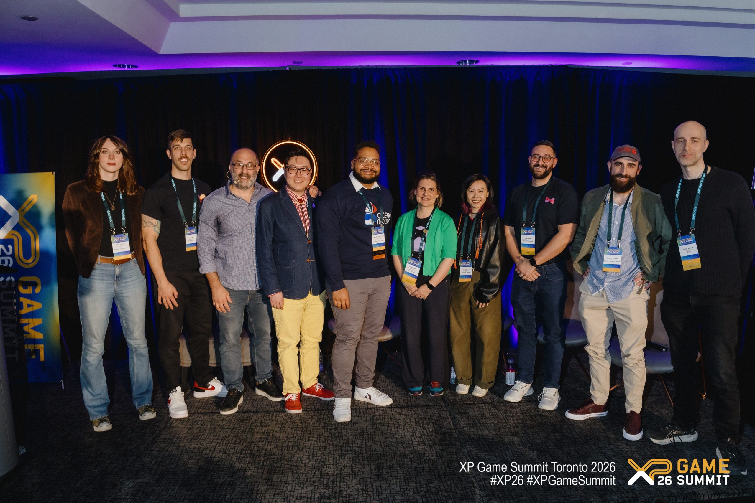 A group of attendees poses at the 'XP Game Summit Toronto 2026,' with a banner displaying 'XP Game Summit 26' and hashtags '#XP26 #XPGameSummit' visible.