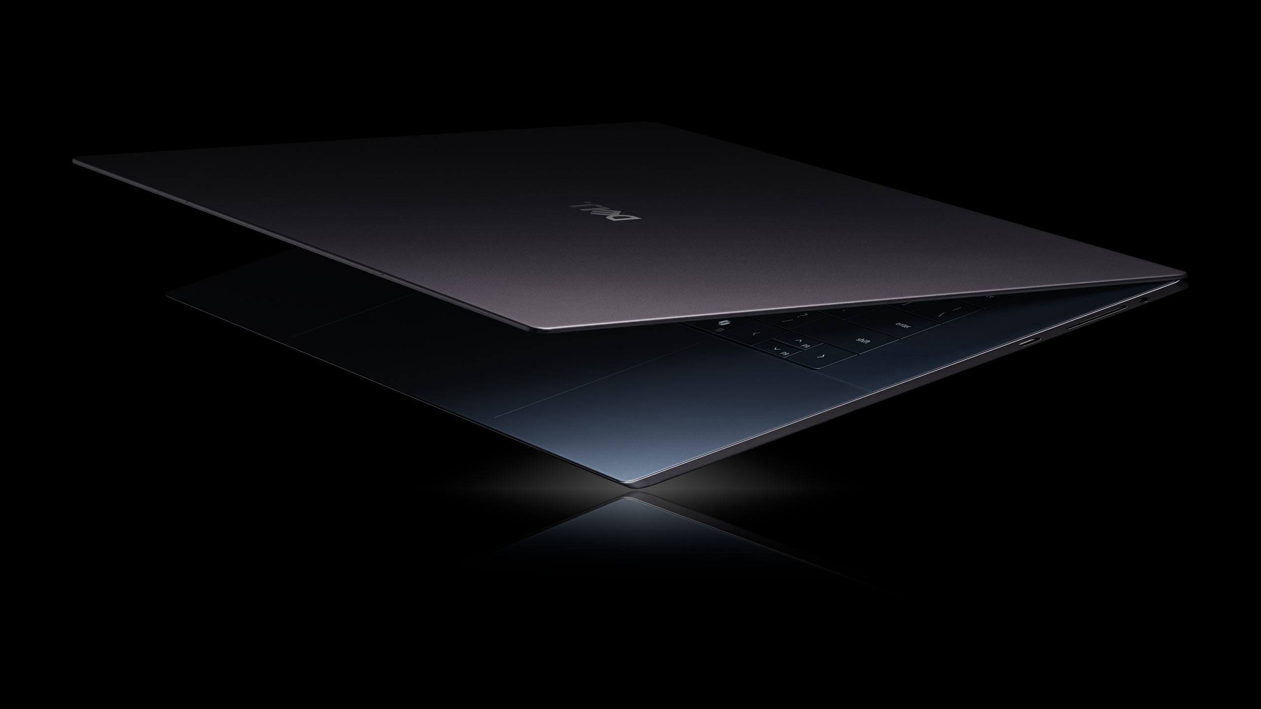 A Dell laptop partially open, showcasing a sleek and minimalistic design, on a black background.