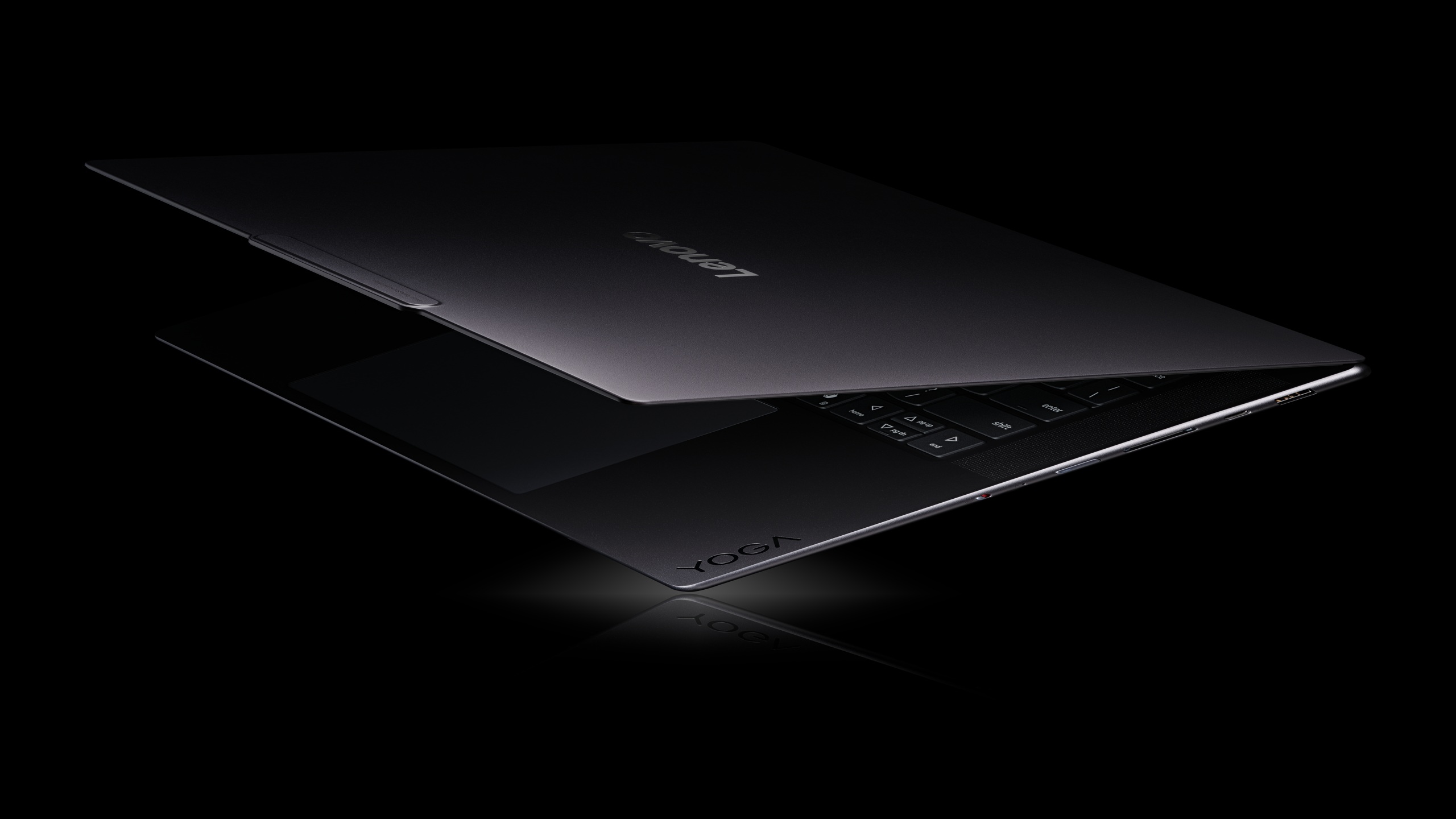 A Lenovo Yoga laptop partially closed, displaying its logo on the lid against a dark background.