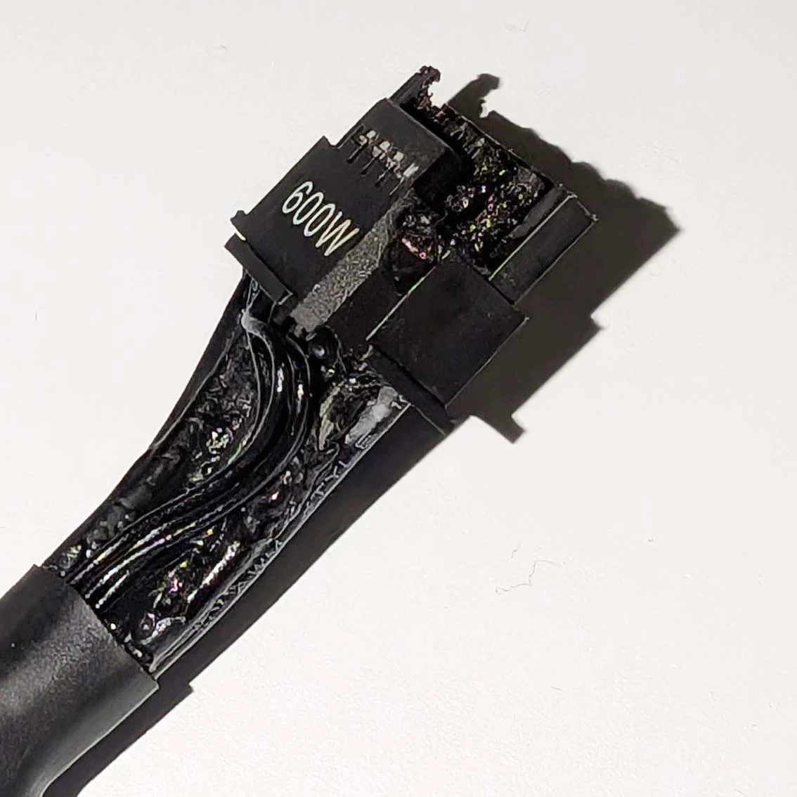 A close-up of a damaged power connector labeled '600W' with melted wiring.