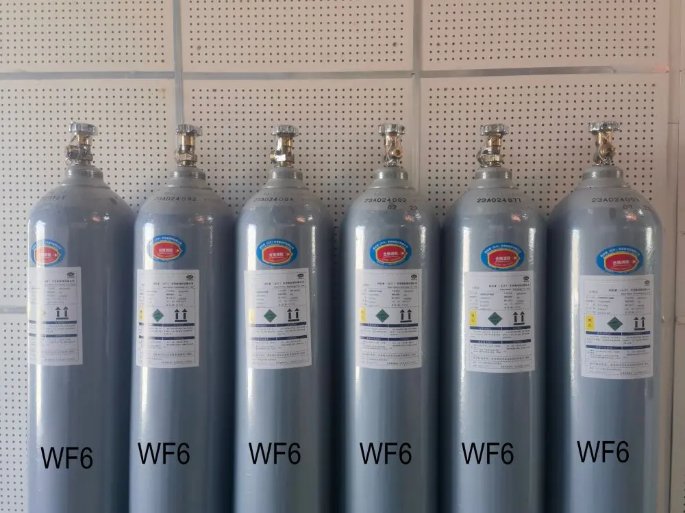 Six grey WF6 gas cylinders are lined up against a perforated wall, each with colored labels and safety information.