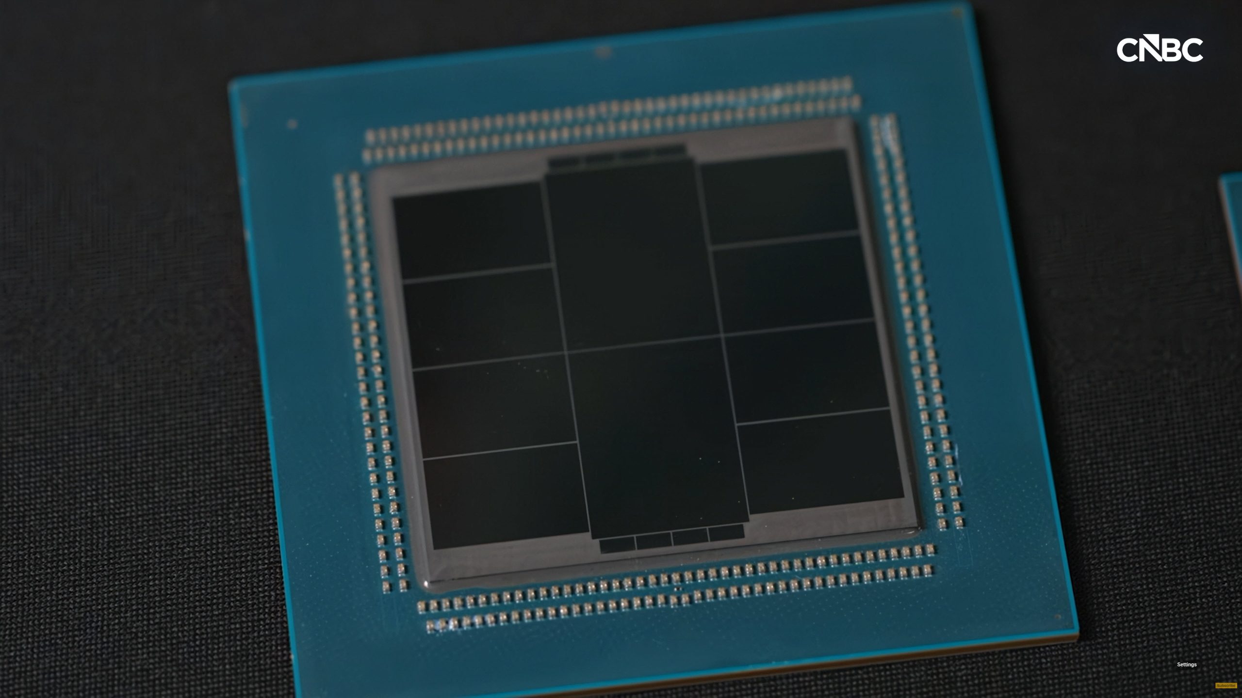 A close-up of an unidentified computer chip on a dark surface, with a 'CNBC' logo in the top right corner.