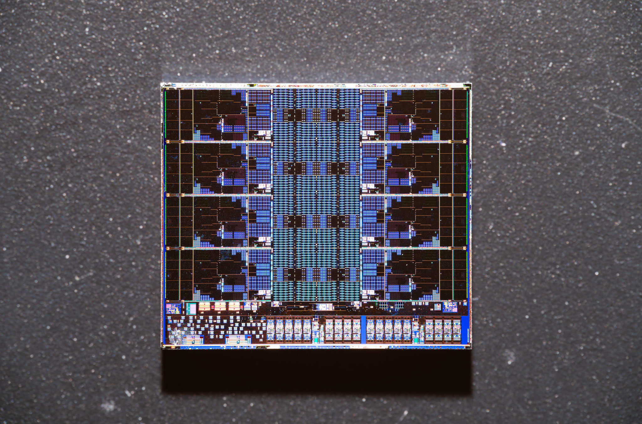 A close-up view of a silicon die showcasing intricate circuit patterns on a textured background.