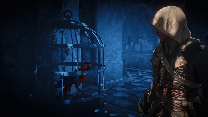 A hooded character stands in a shadowy hallway looking at a red parrot inside a metal cage in the game 'Assassin's Creed IV: Black Flag.'