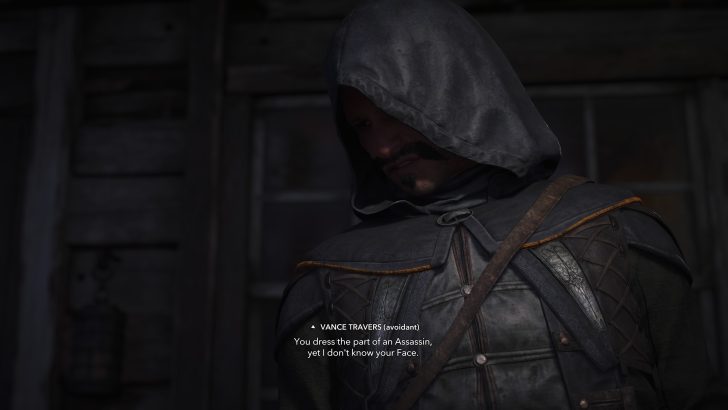 A character in 'Assassin's Creed' wearing a hooded cloak stands in front of a wooden structure with on-screen text from Vance Travers saying, You dress the part of an Assassin, yet I don't know your face.