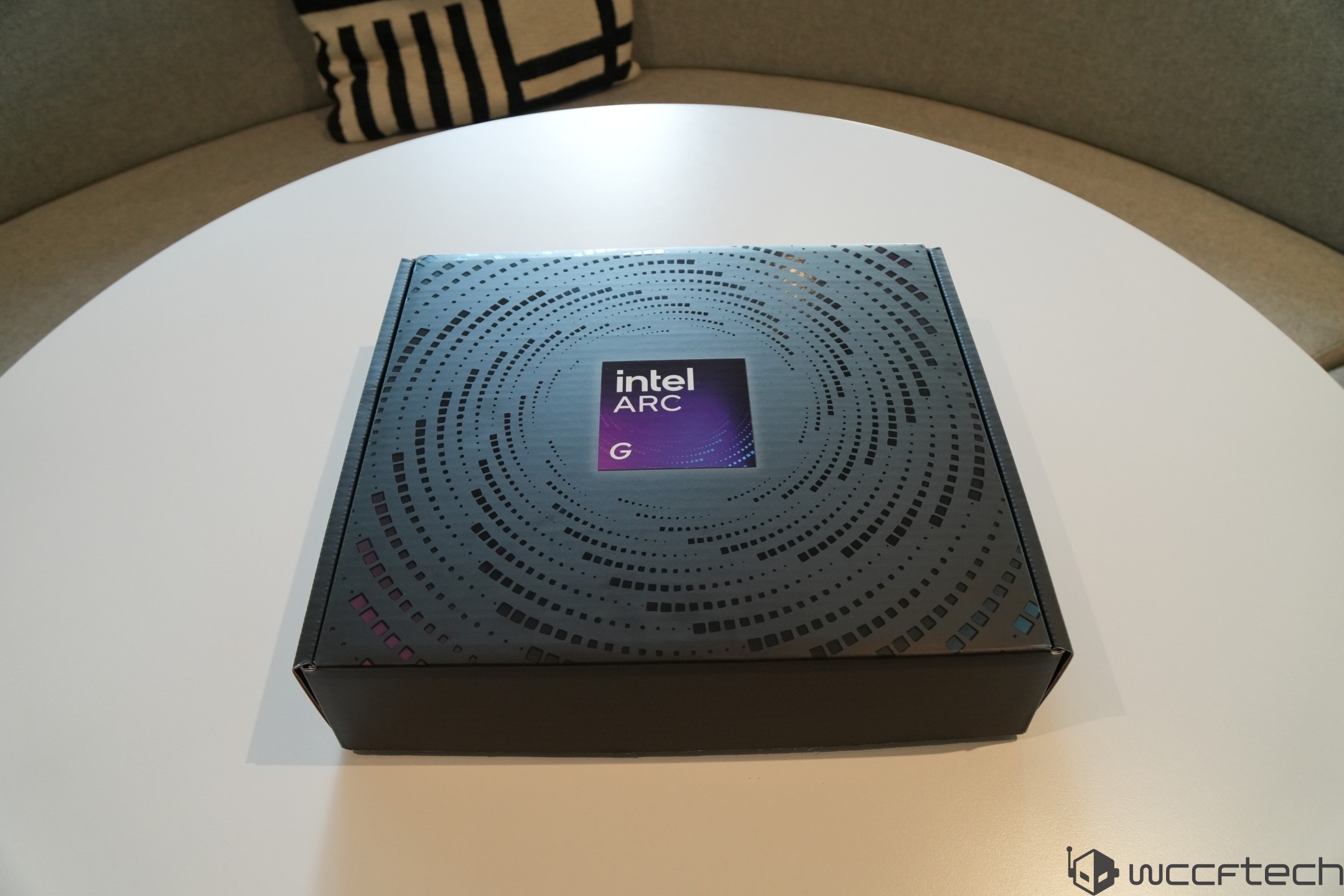 A box labeled 'Intel Arc G' is resting on a round white table.