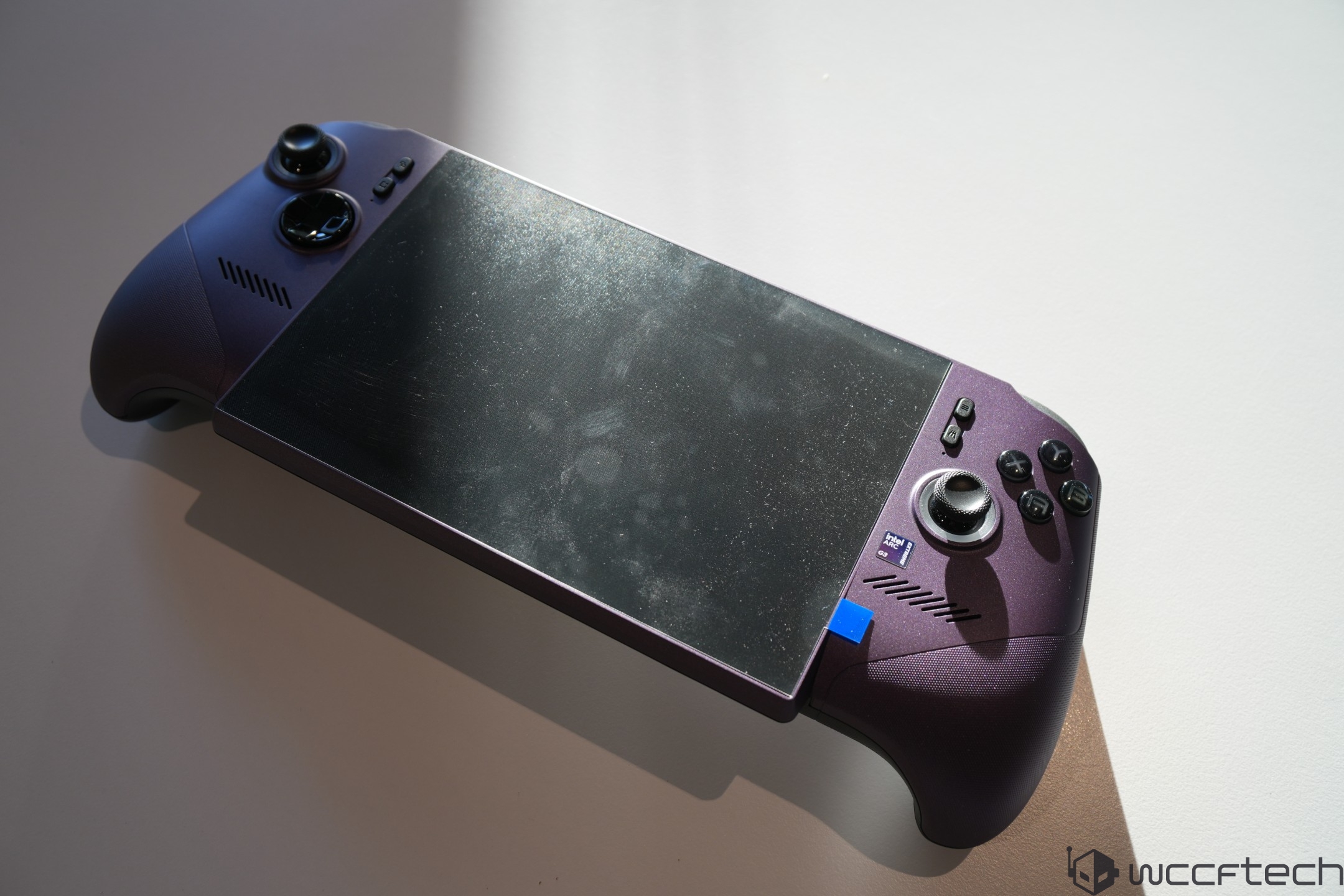The image shows an ASUS ROG Ally portable gaming console with visible control buttons and joysticks on a flat surface.
