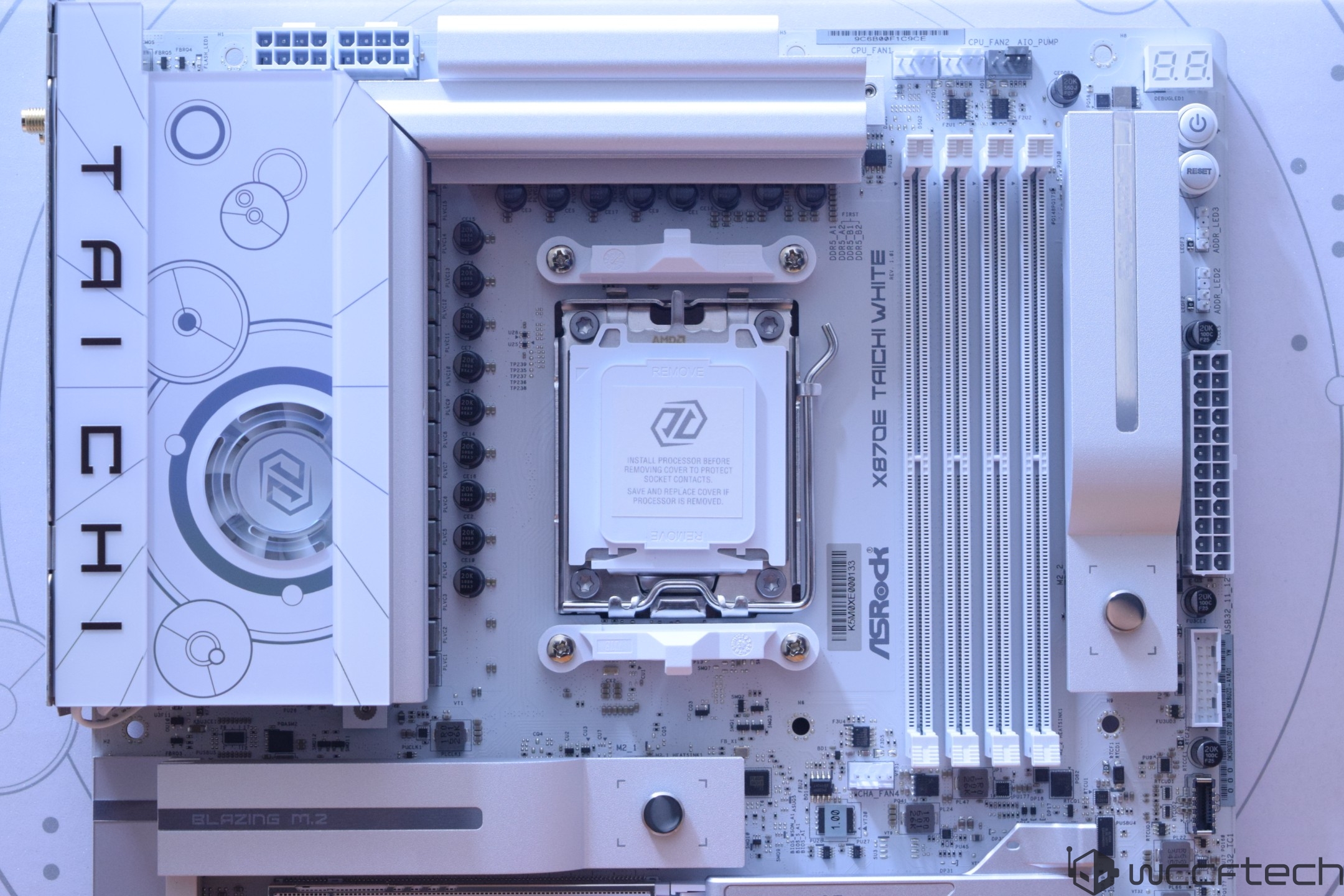ASRock X670E Taichi White motherboard featuring a socket labeled 'AMD' with four RAM slots and 'Blazing M.2' slot visible.