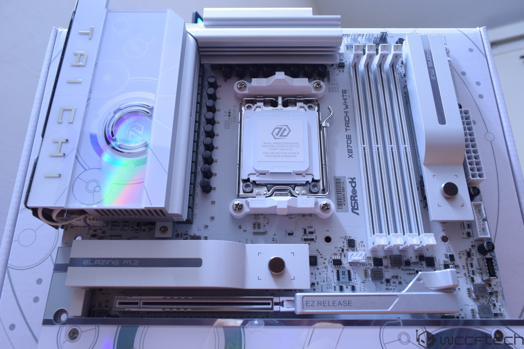 The ASRock X670E Taichi White motherboard features branding and components such as 'BLAZING M.2' and 'EZ RELEASE.'