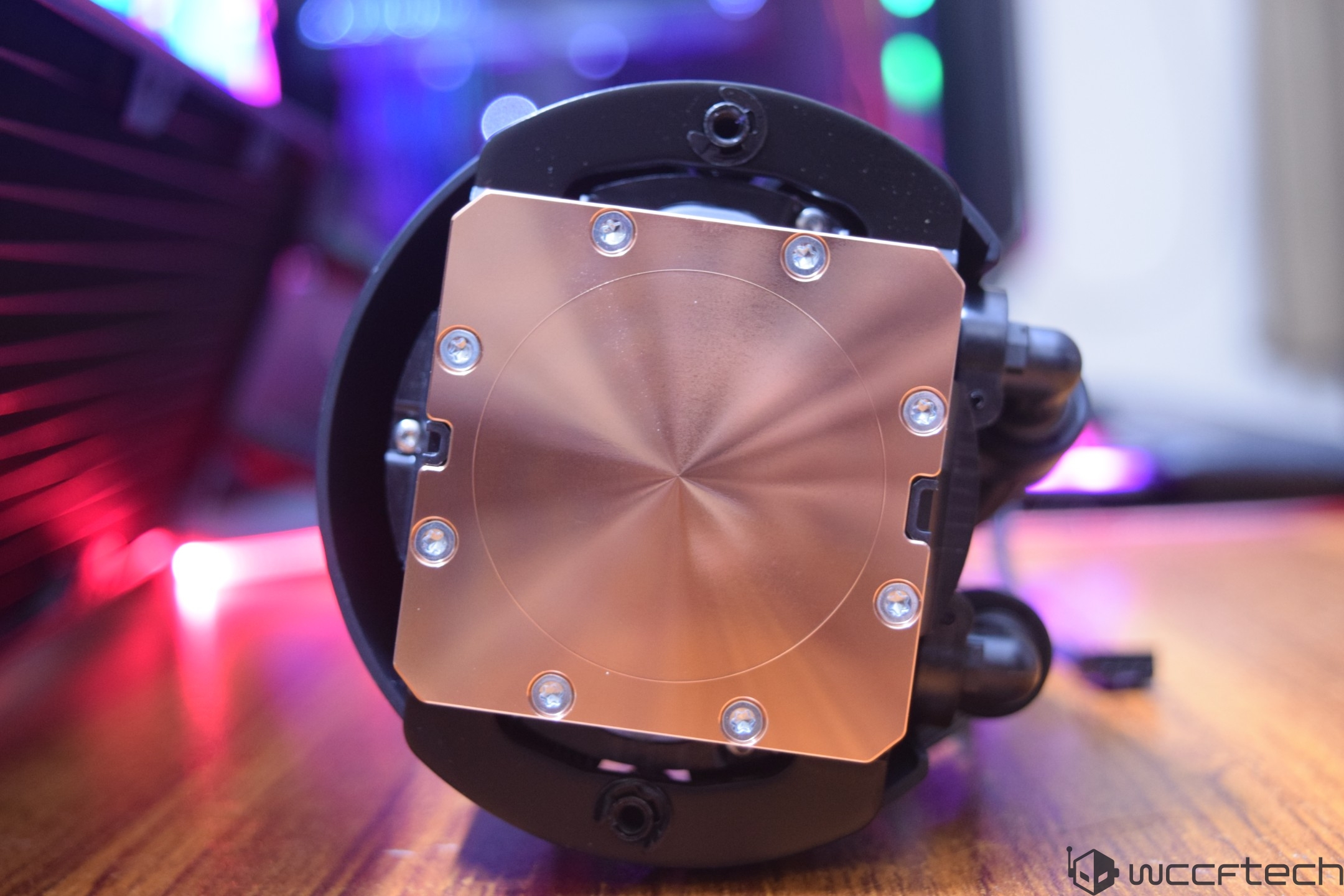 A close-up of a liquid cooler with a copper base and mounting screws.