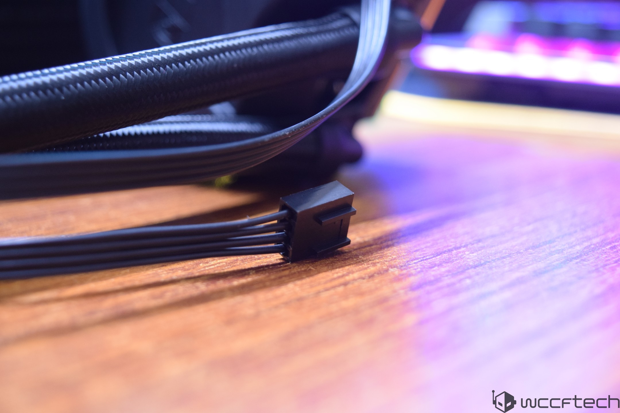 A close-up of a black power connector with multiple cables on a wooden surface.
