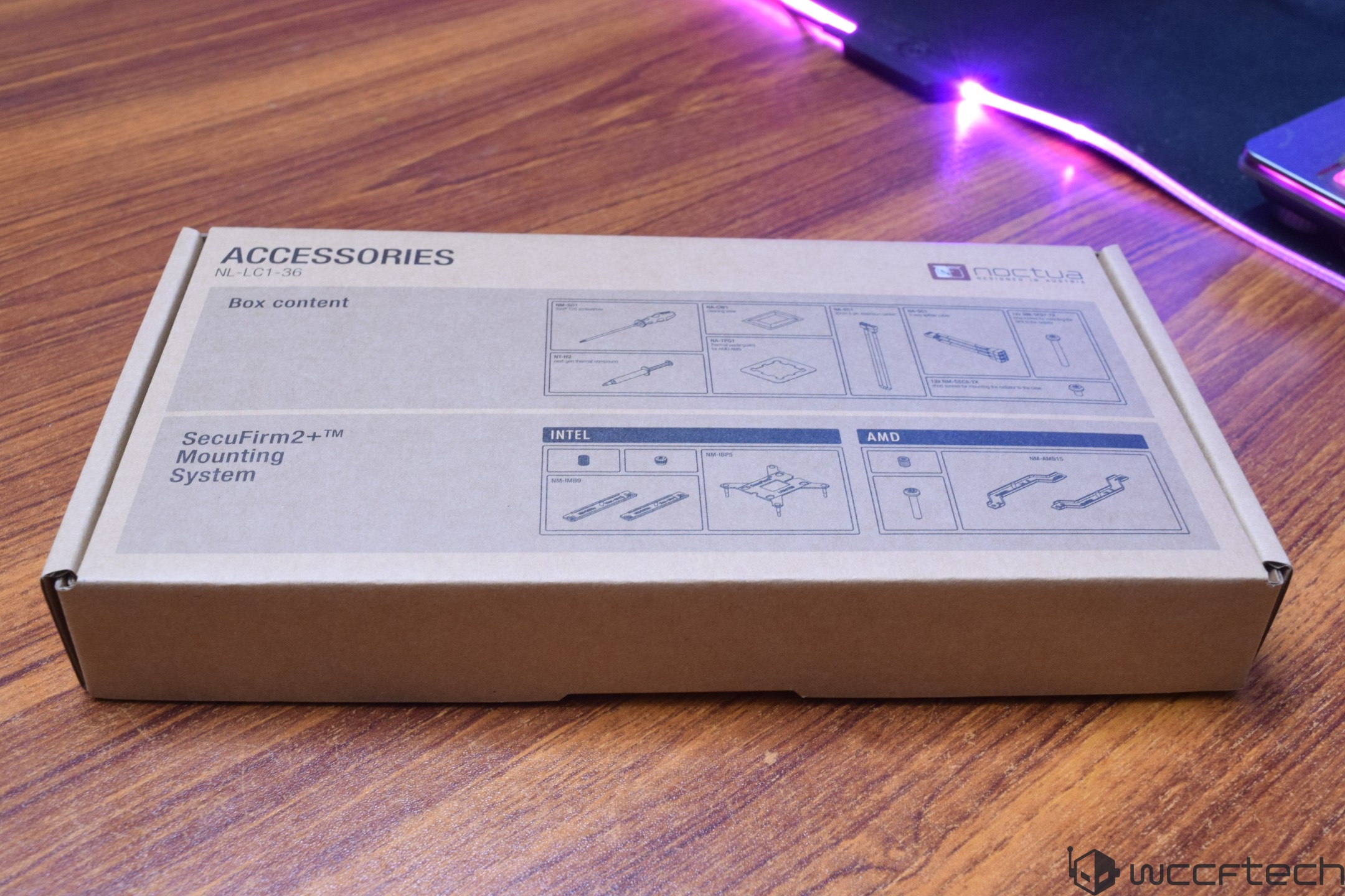Noctua SecuFirm2+ mounting system box labeled NL-LC1-36 with diagrams for Intel and AMD setups on a wooden surface.