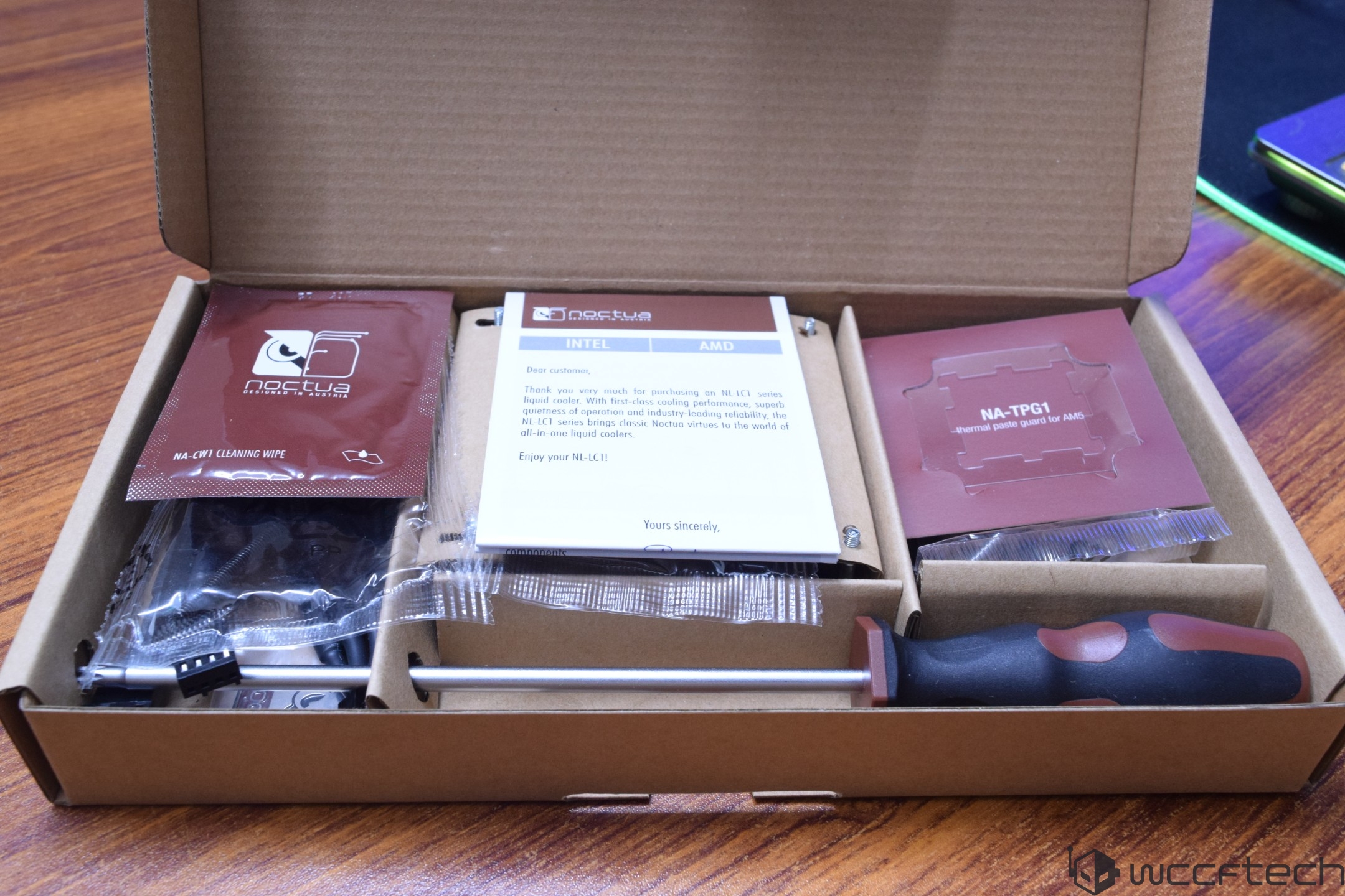 A Noctua NL-LC1 series liquid cooler package includes a 'NA-CW1 cleaning wipe,' a note for 'INTEL' and 'AMD,' a 'NA-TPG1 thermal paste guard for AM5,' and a screwdriver.