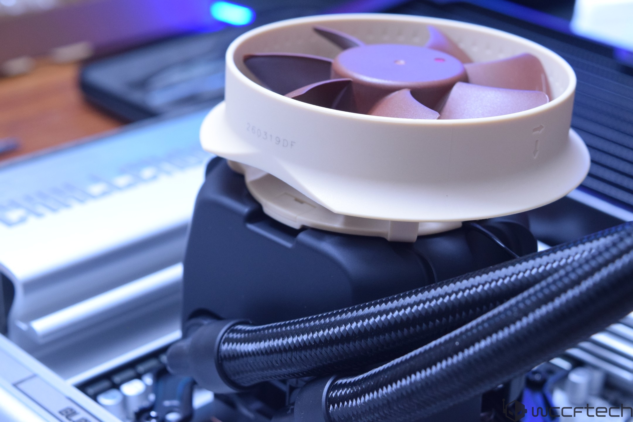 A Noctua CPU cooler is mounted on a motherboard, highlighting its beige and brown fan with braided cables.
