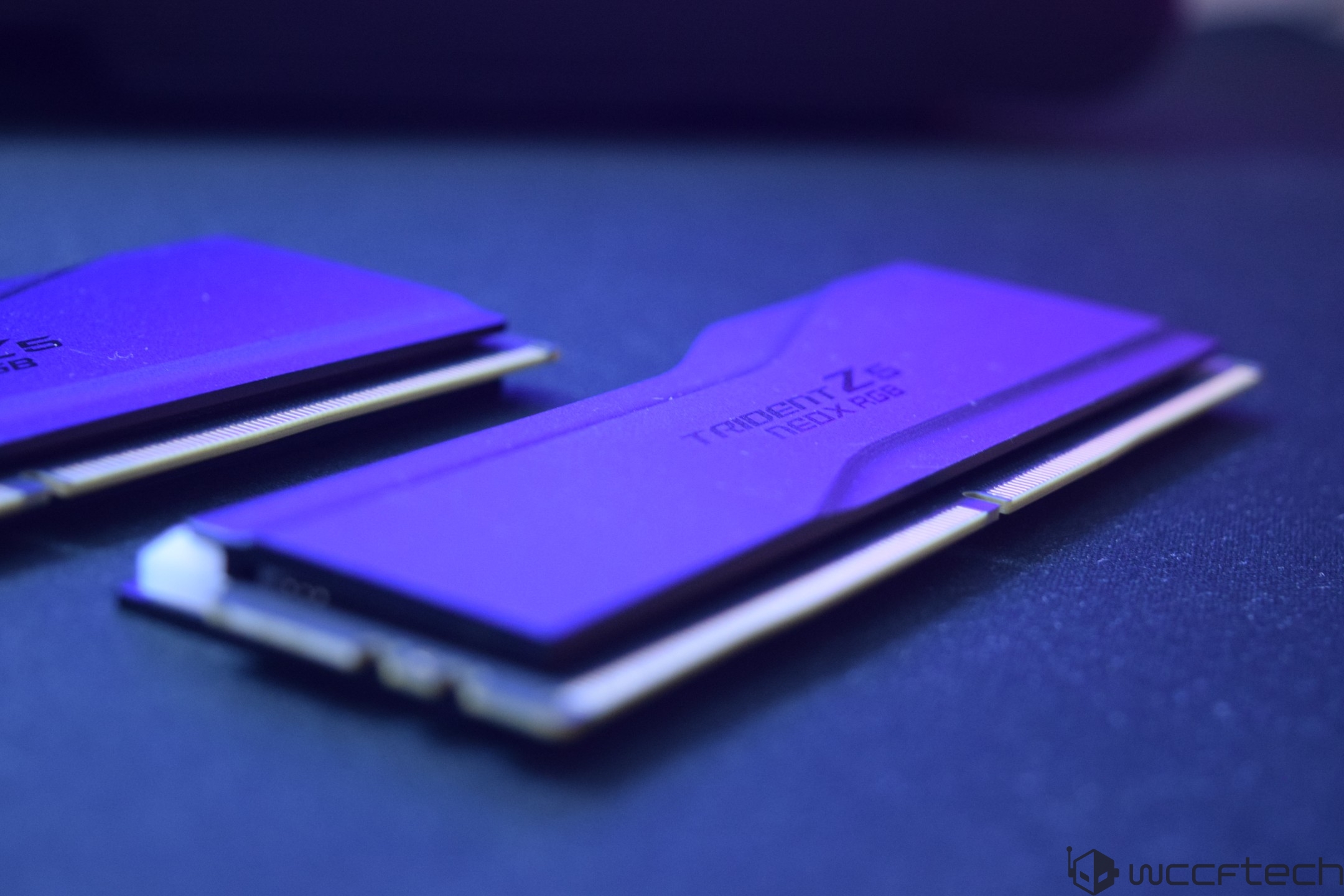 A close-up of two purple G.SKILL Trident Z5 NeoX RGB RAM modules resting on a surface.