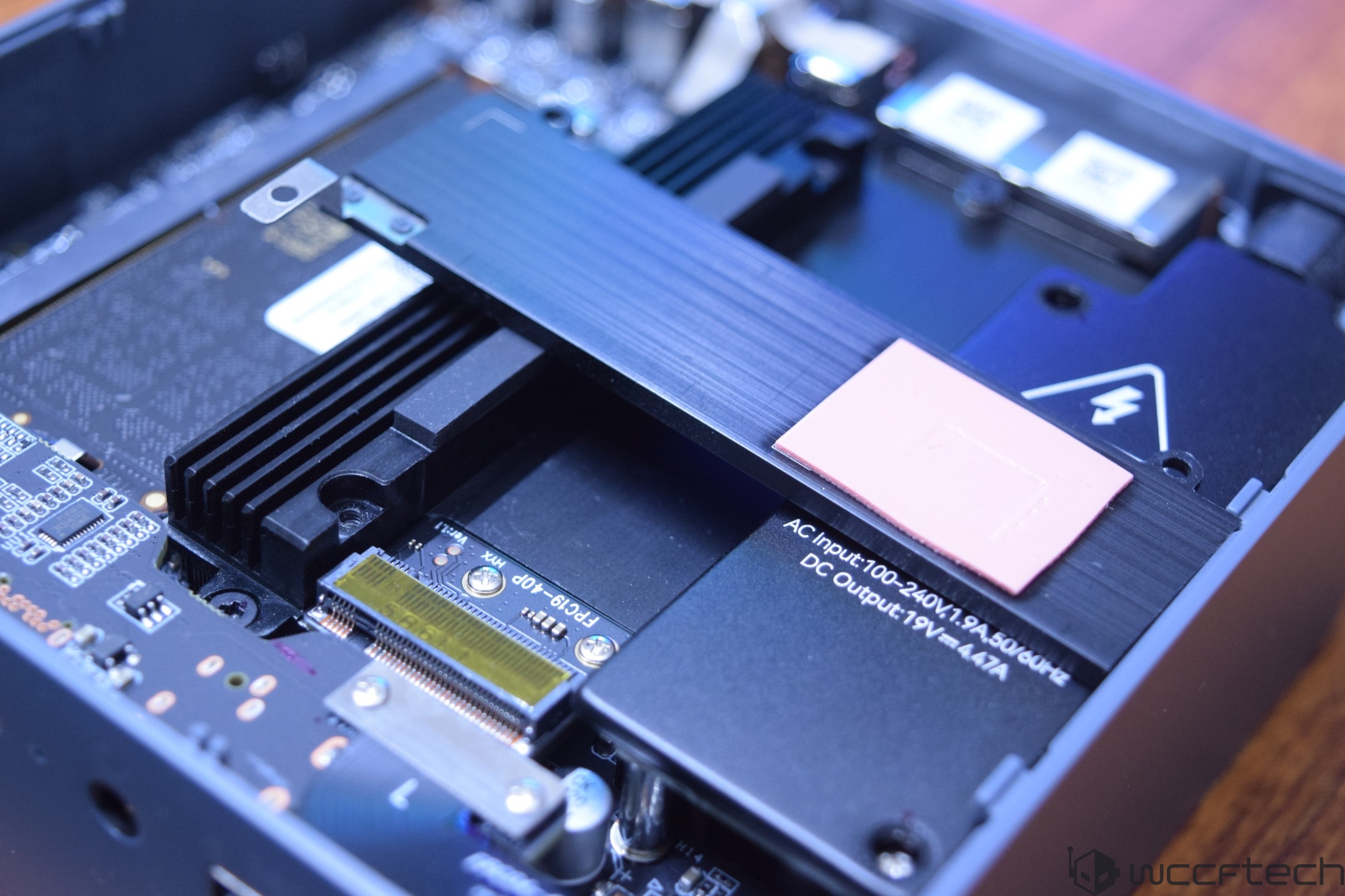 An open PC case showing a Thunderbolt port and an M.2 SSD slot with visible text 'AC Input:100-240V' and 'DC Output:19V'.
