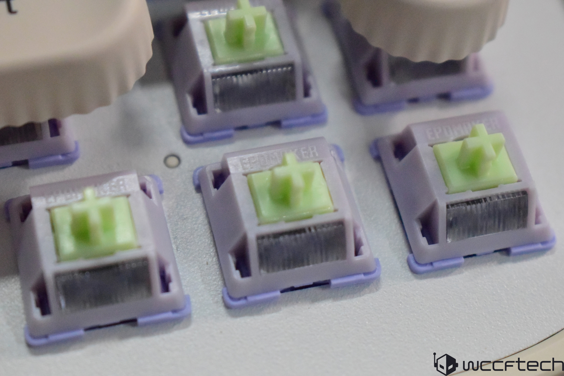 Close-up of green Epomaker mechanical keyboard switches on a gray surface.