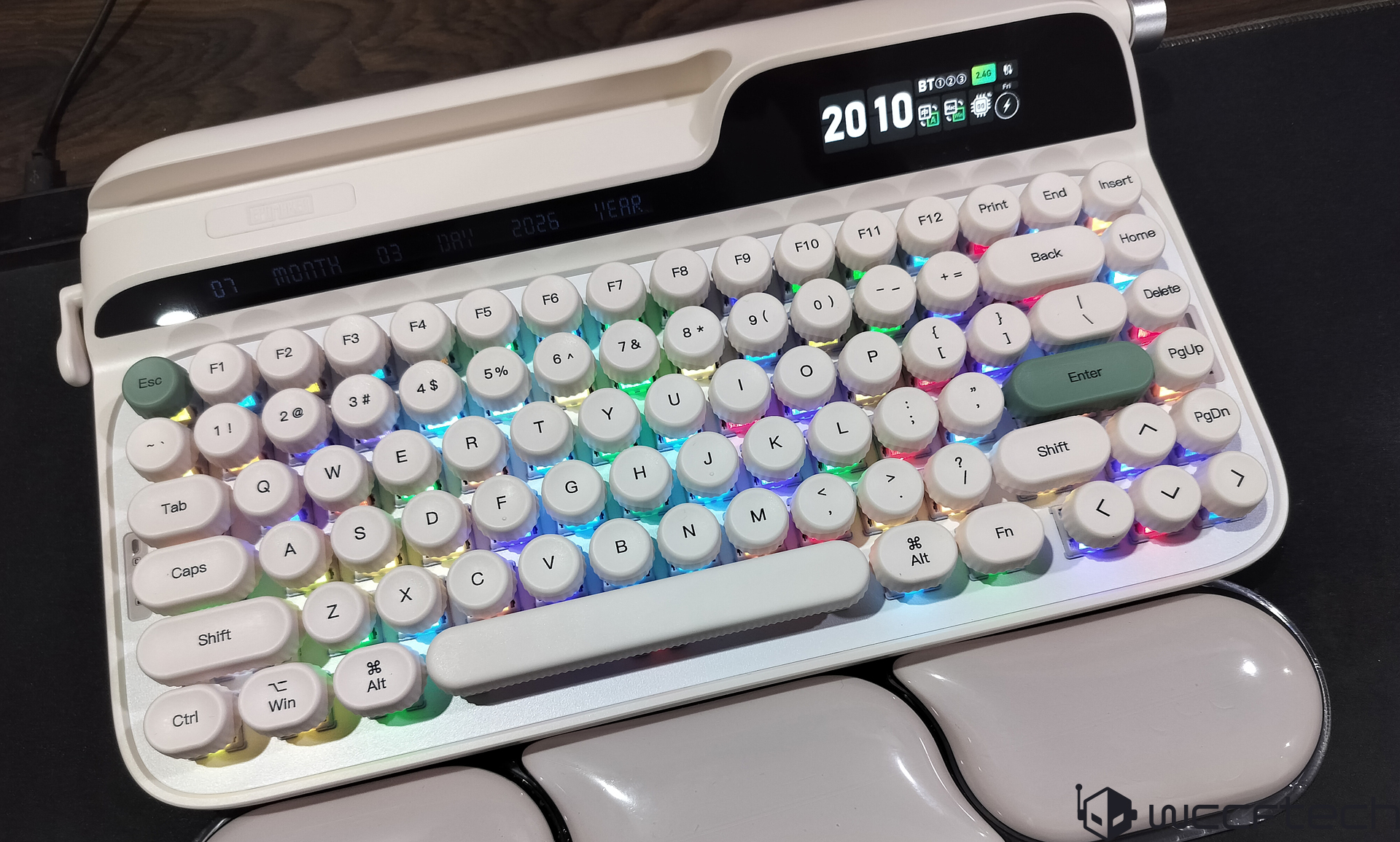 A white mechanical keyboard with round, retro-style keys and RGB backlighting displays the time '20:10' and Bluetooth connectivity details on a small digital screen.