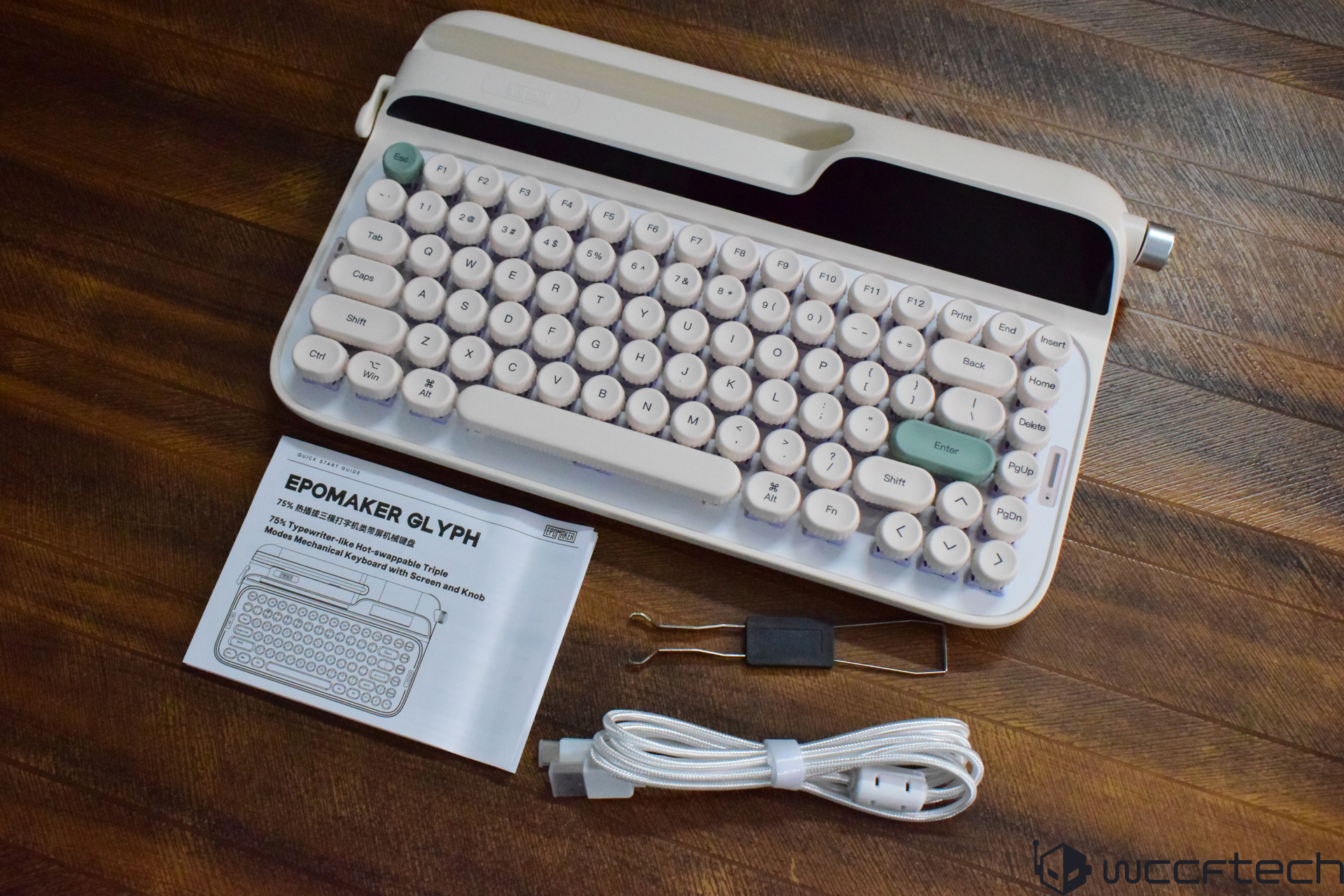 The Epomaker Glyph keyboard is shown with a user manual, keycap puller, and USB cable on a wooden surface.