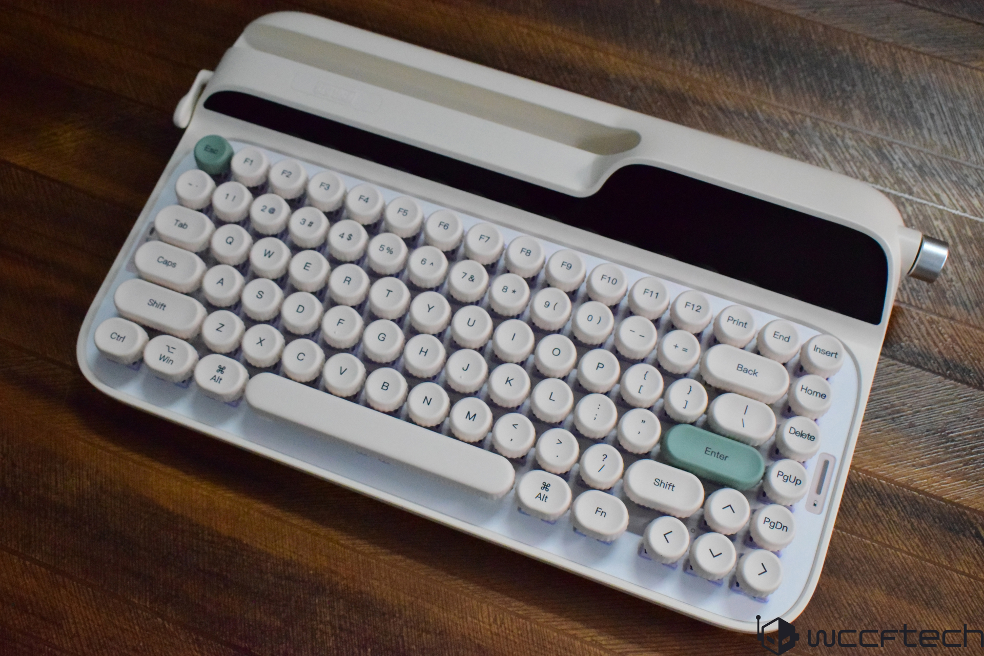 A retro-style white keyboard featuring round keys and a green 'Enter' key, designed with a built-in stand for devices.
