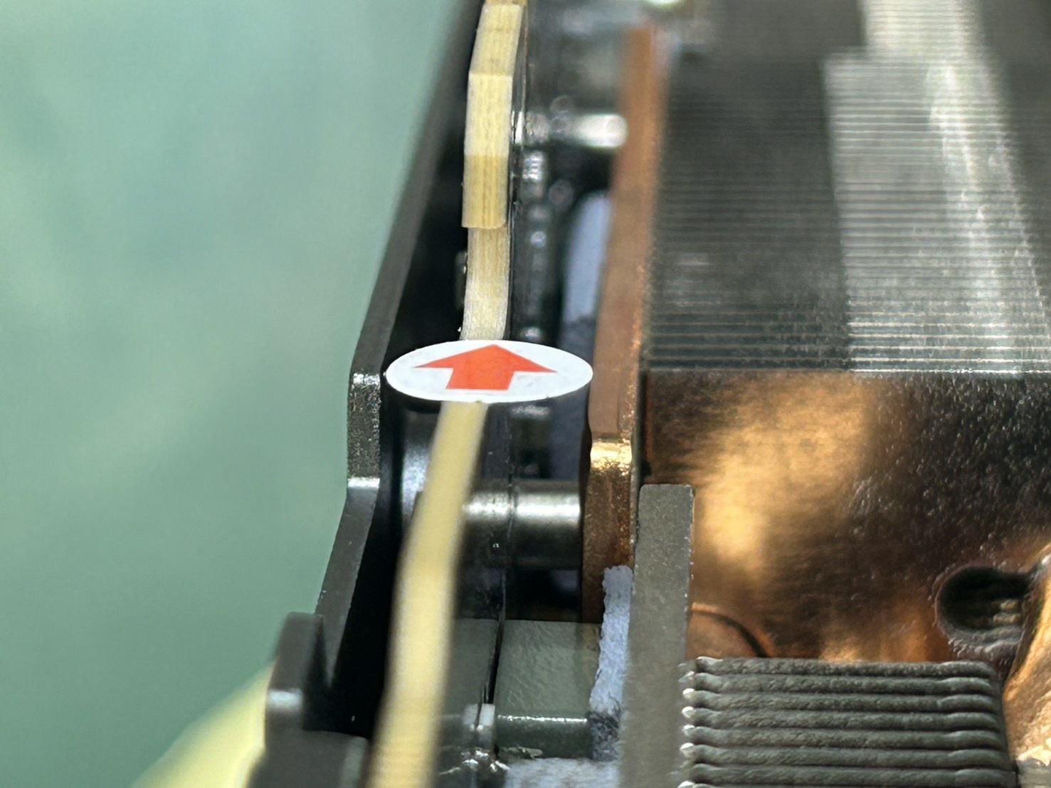 A close-up of a GPU's heat sink shows a white sticker with a red arrow indicating airflow direction.
