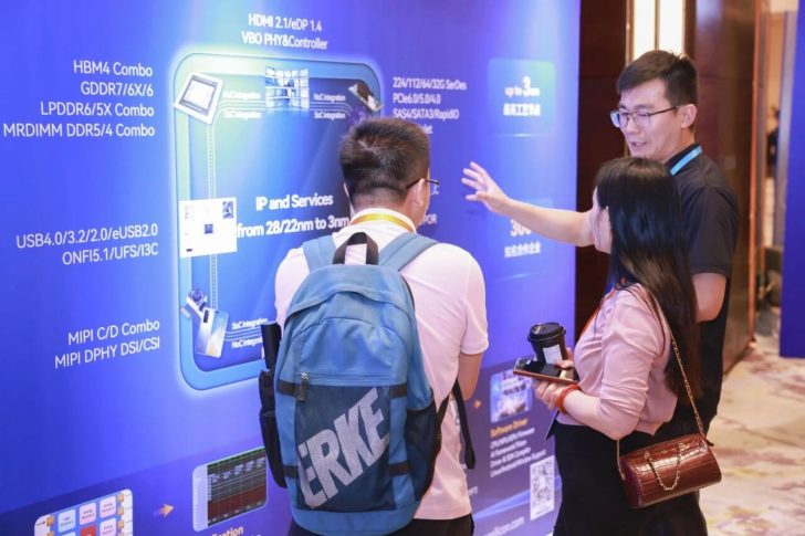 Three people examine a presentation board displaying various technology specifications, including 'HBM4 Combo' and 'USB4/3.2/2.0/eUSB2.0.'