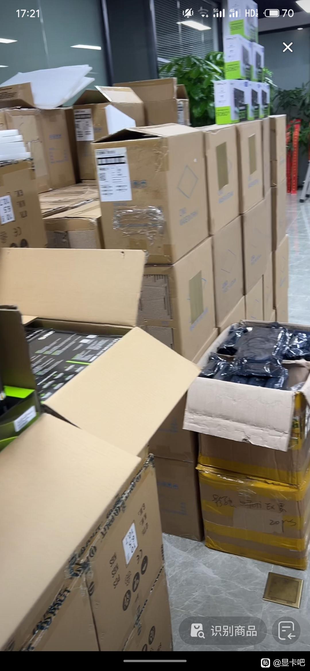 A stack of open cardboard boxes displaying NVIDIA GeForce graphics card packaging in an office setting surrounded by more sealed boxes.