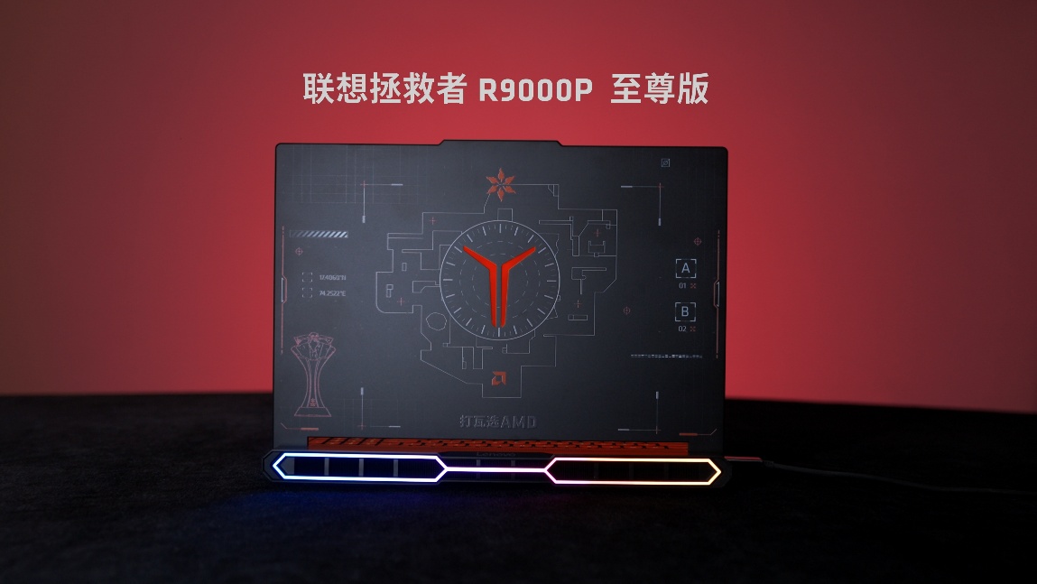 The Lenovo Legion R9000P laptop with an AMD design is displayed against a red background, featuring a lit-up base and intricate graphics on the lid.