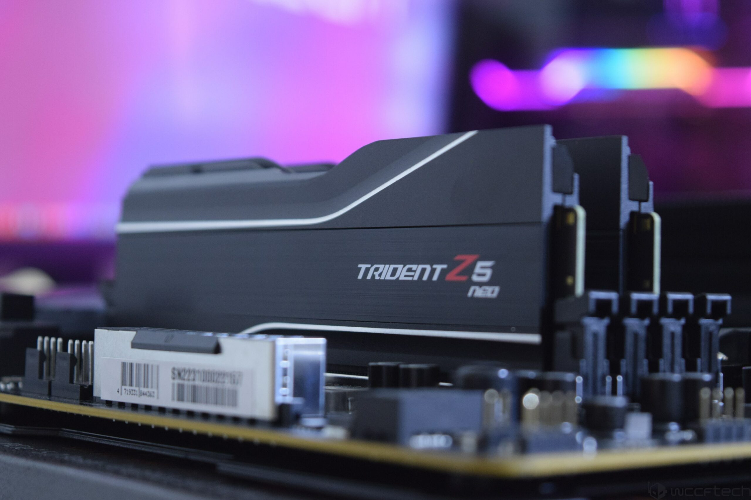 G.Skill Trident Z5 Neo RAM modules are installed on a motherboard with a blurred RGB-lit background.