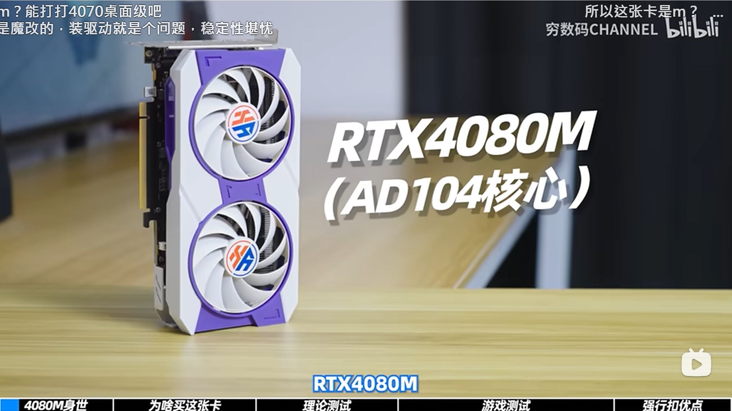A white and purple graphics card with dual fans is displayed on a table, with on-screen text reading 'RTX4080M (AD104核心)'.