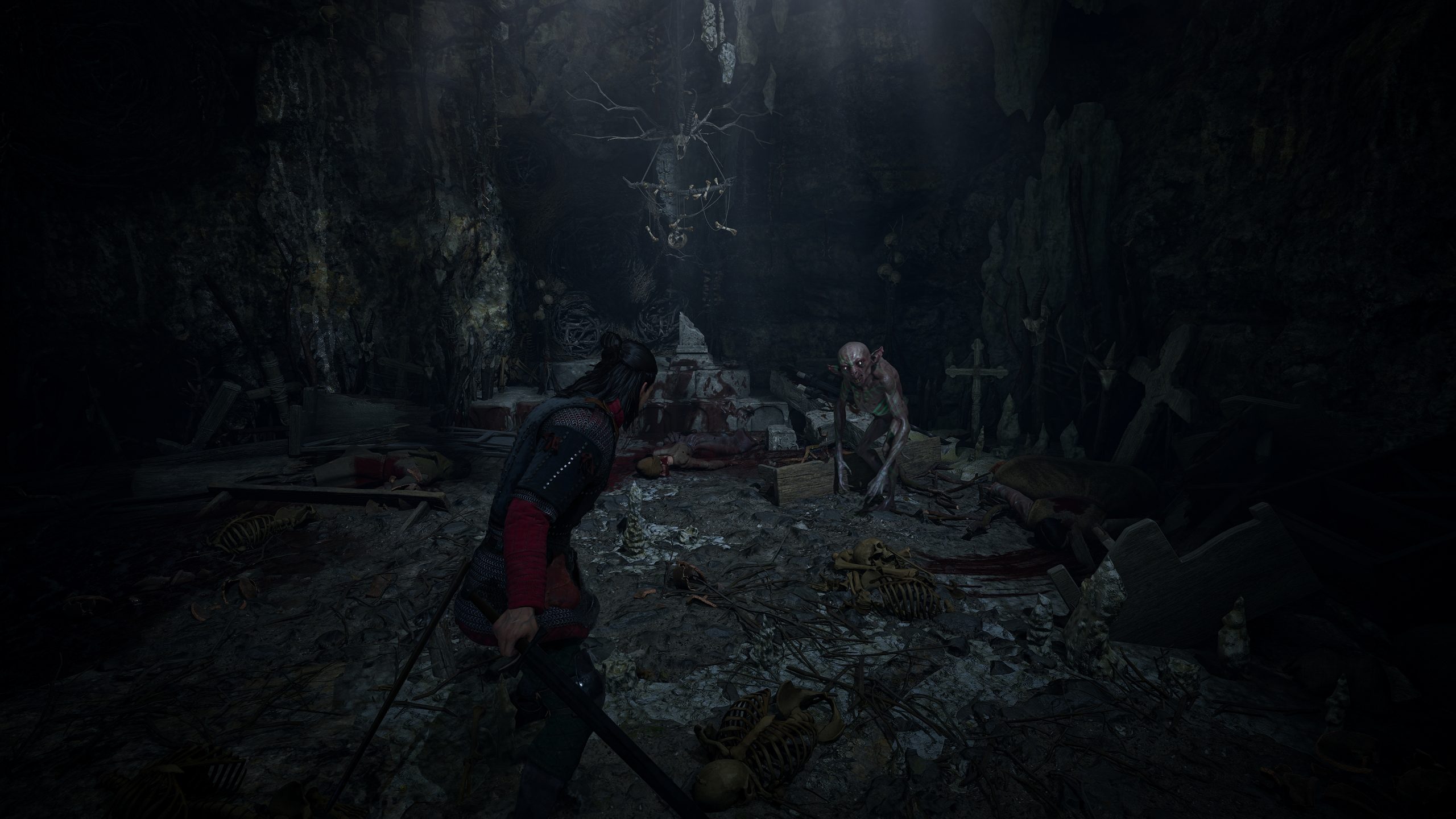 A character in Lords of the Fallen confronts a monstrous creature in a dark, cave-like environment filled with bones and eerie decorations.