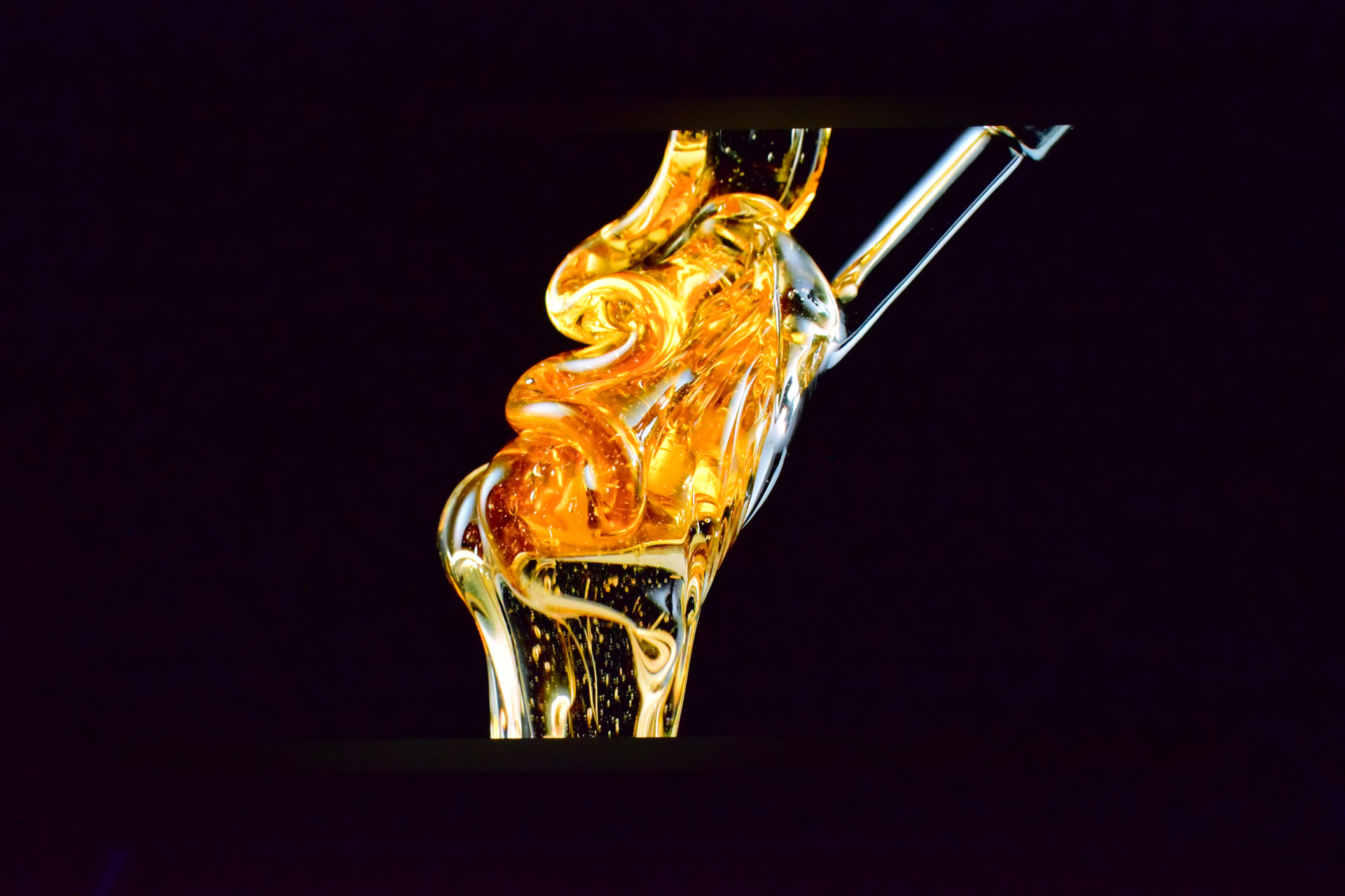 A close-up image shows a swirling stream of viscous golden liquid against a dark background.