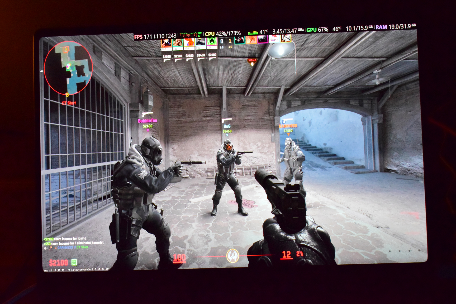 A gameplay scene from 'Counter-Strike: Global Offensive' shows a first-person view with three players labeled BubbleTee, BuG, and DRAXIBE89 in a warehouse area, alongside on-screen text displaying 'FPS 171' and various CPU and GPU metrics.
