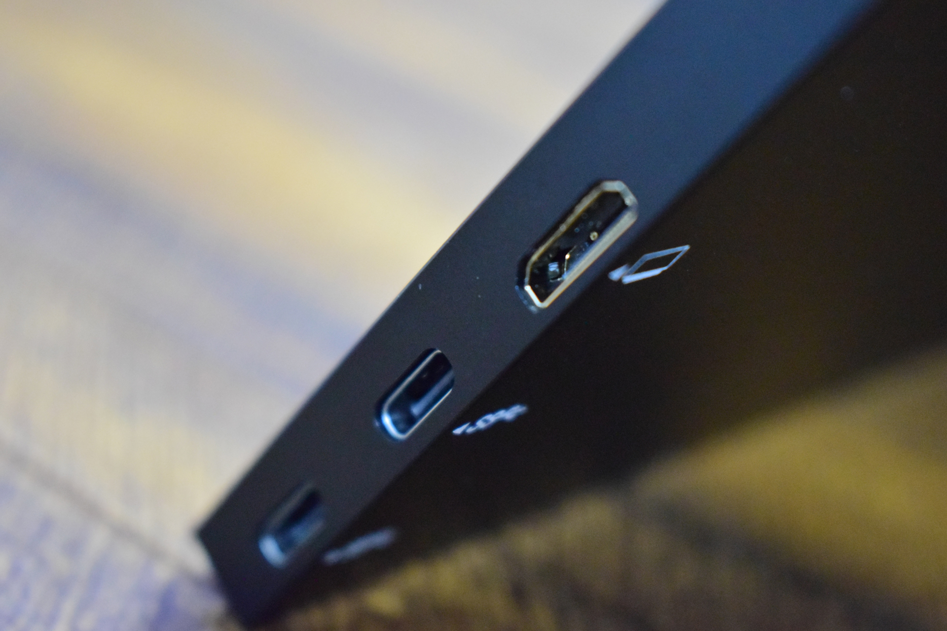 A close-up of a black device showing three ports, including a standard USB, two USB-C ports, and a display port icon next to one port.