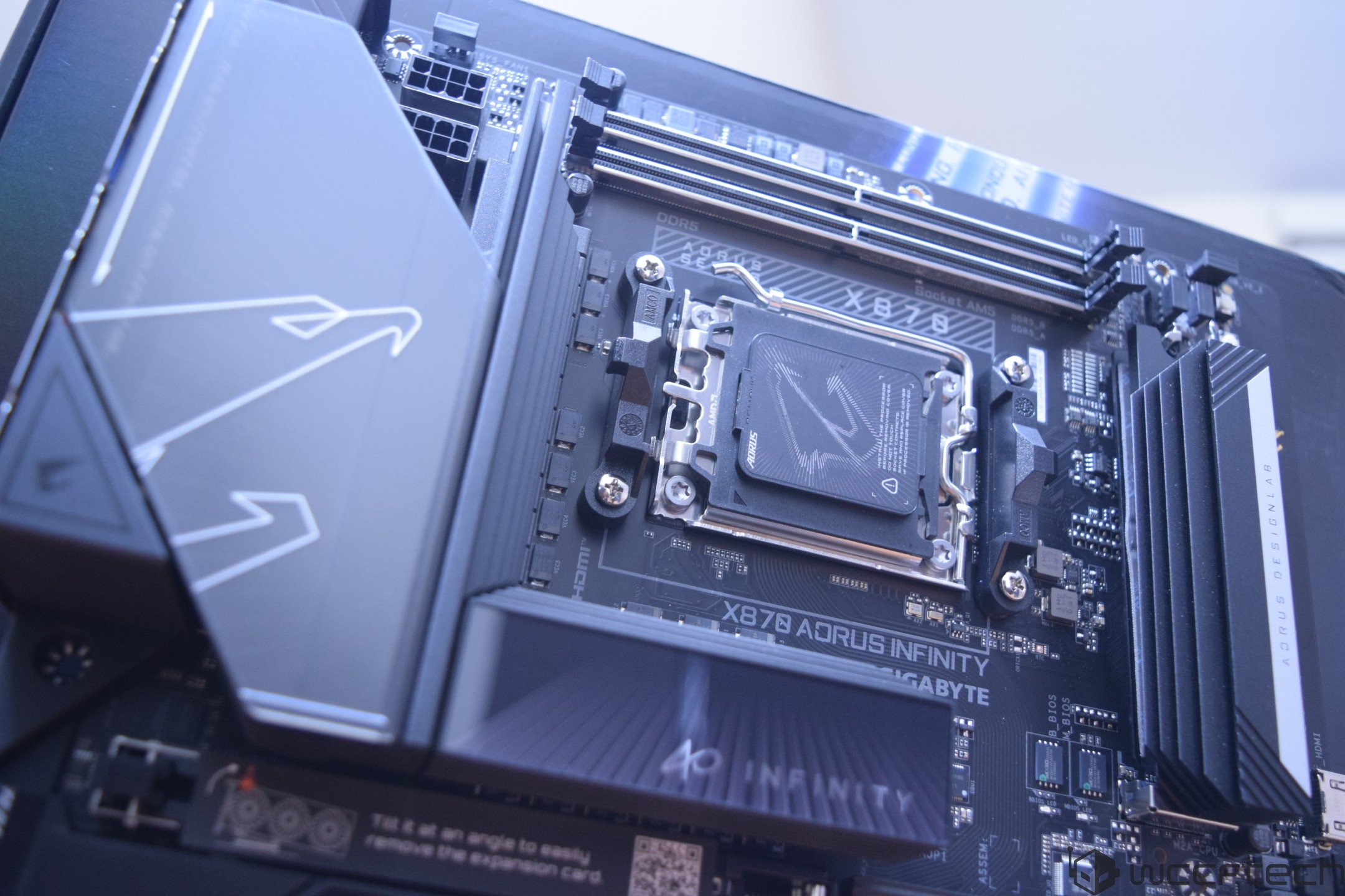 The image shows a Gigabyte X878 AORUS INFINITY motherboard with visible AORUS branding and socket AM5 design, featuring DDR5 memory slots.