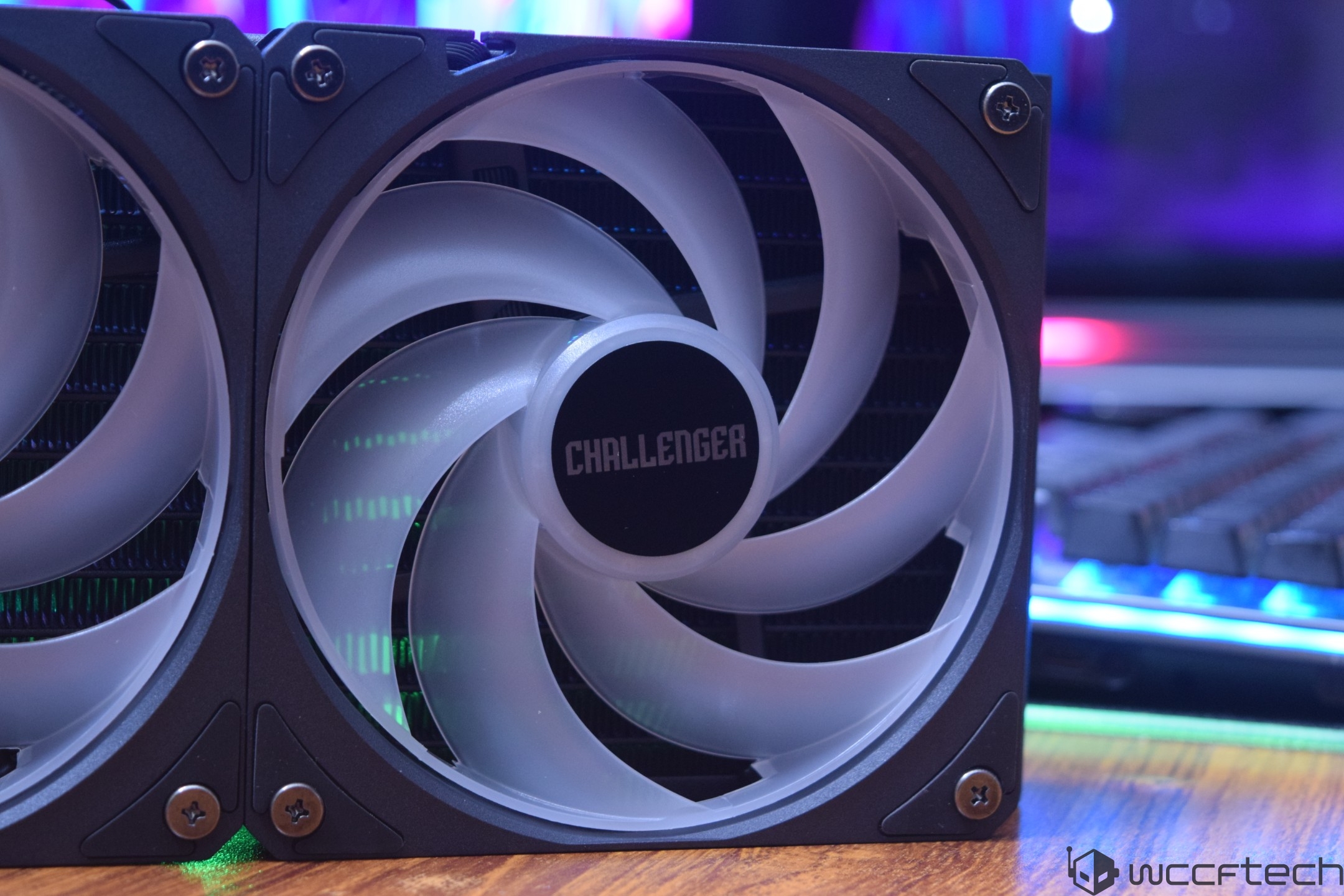 A close-up of a computer cooling fan with the label 'CHALLENGER' in the center, set against a background featuring a colorful, illuminated keyboard.
