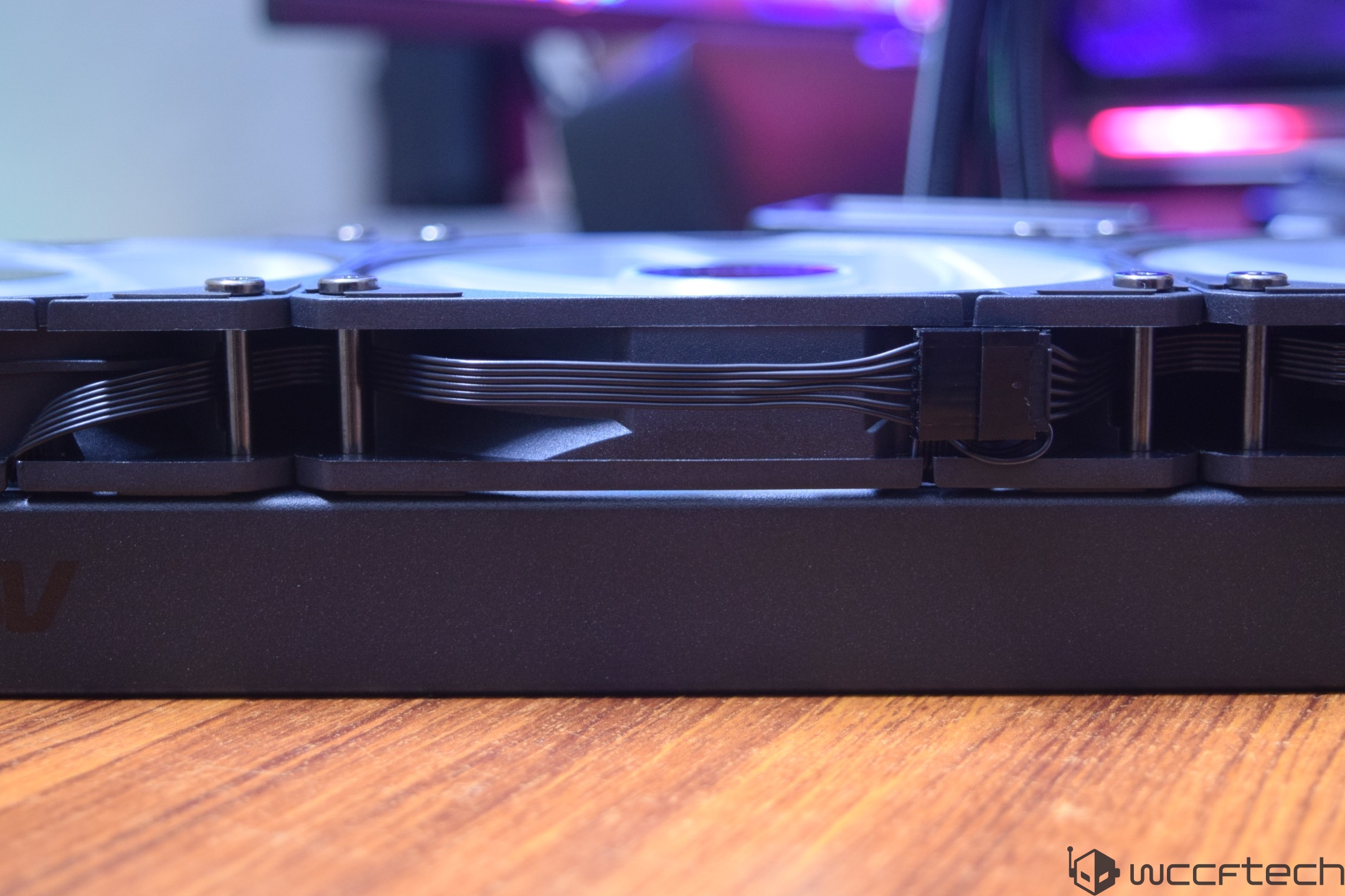 A close-up of a black unbranded graphics card with visible power cables and cooling fans resting on a wooden surface.
