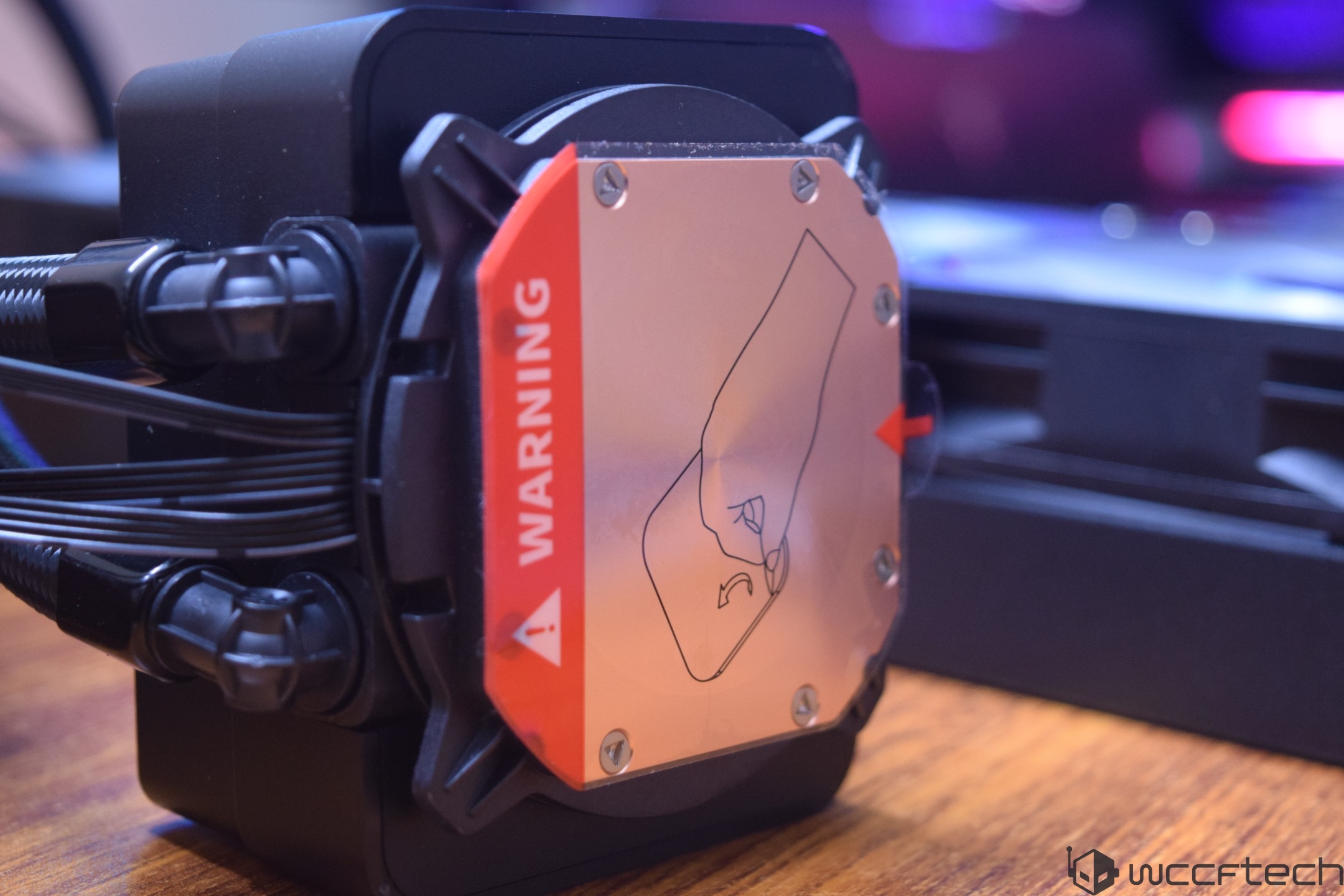 A close-up of a CPU cooler with an orange label displaying 'WARNING' and an illustration indicating proper handling.