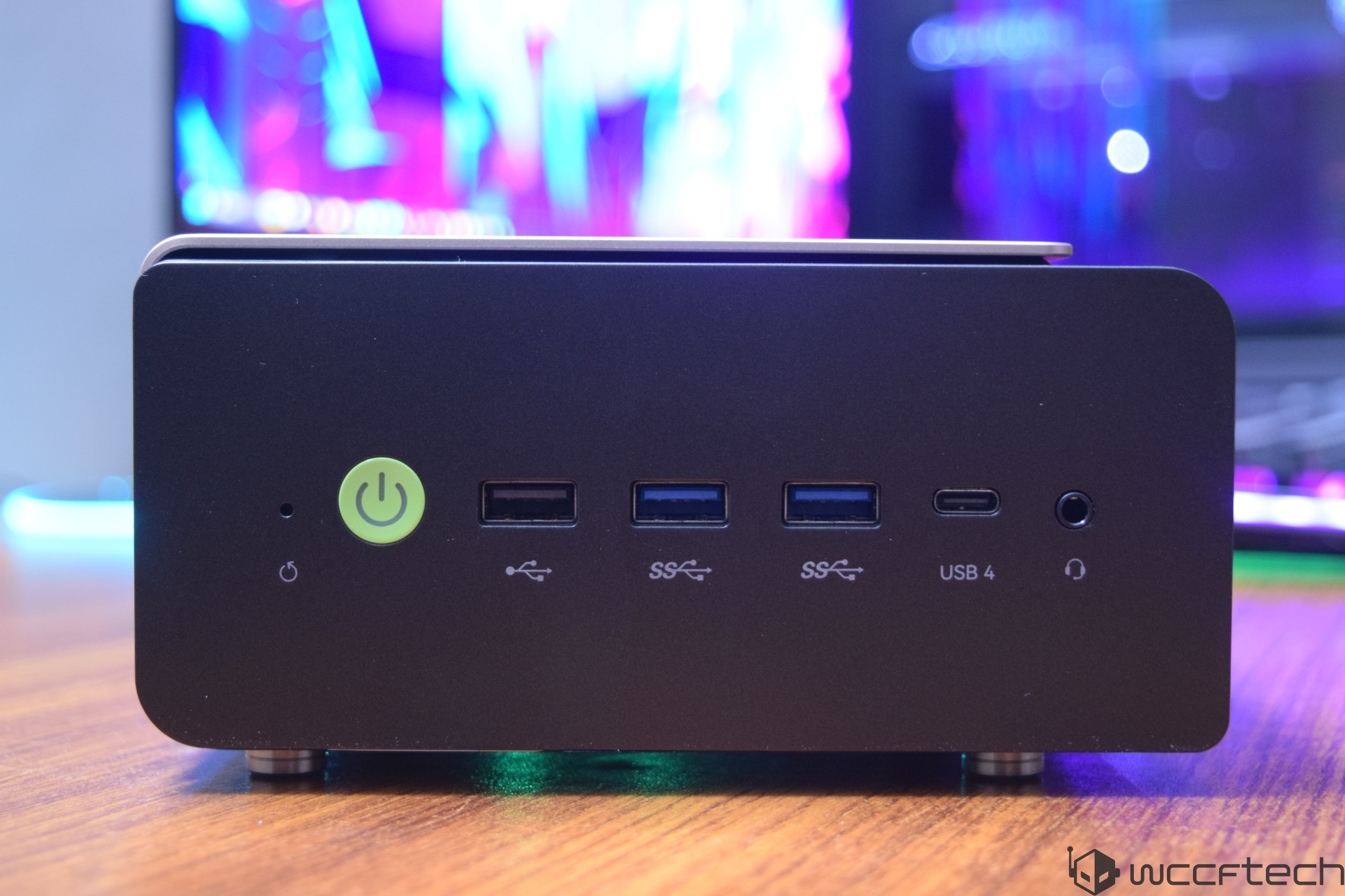 The front panel of a mini PC features a green power button, two USB Type-A ports labeled 'SS,' a USB Type-C port labeled 'USB 4,' and an audio jack.