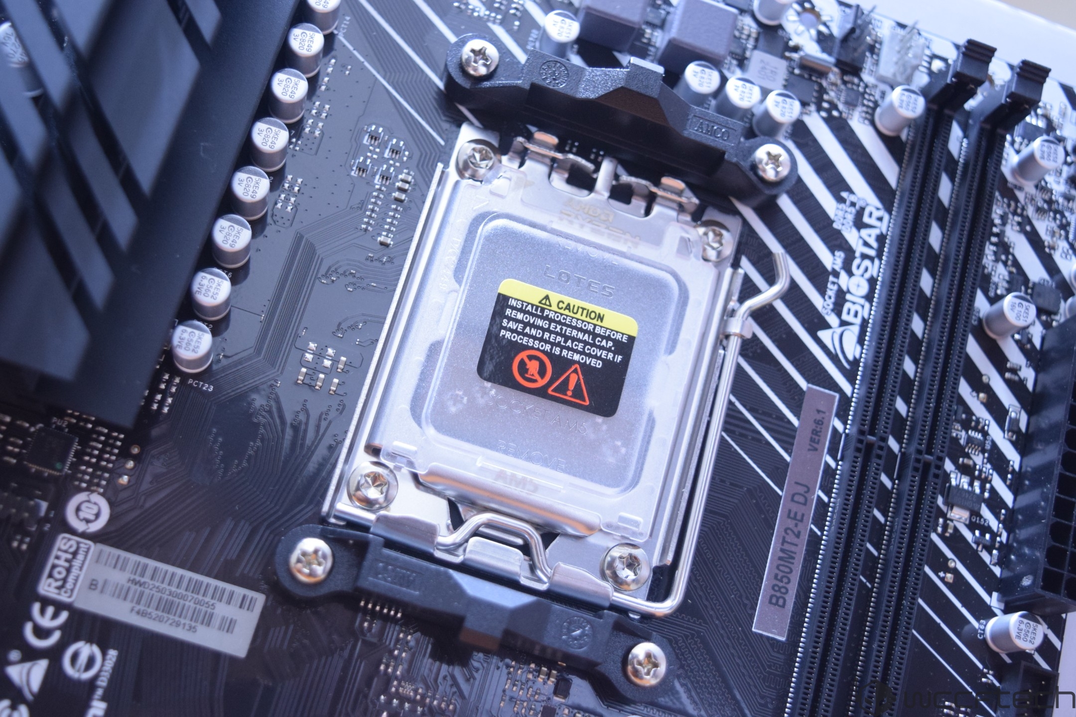 A close-up of a Biostar motherboard showing the LGA1700 socket with a 'Caution' sticker, and model label 'B660M12-E DJ Ver: 6.1.'