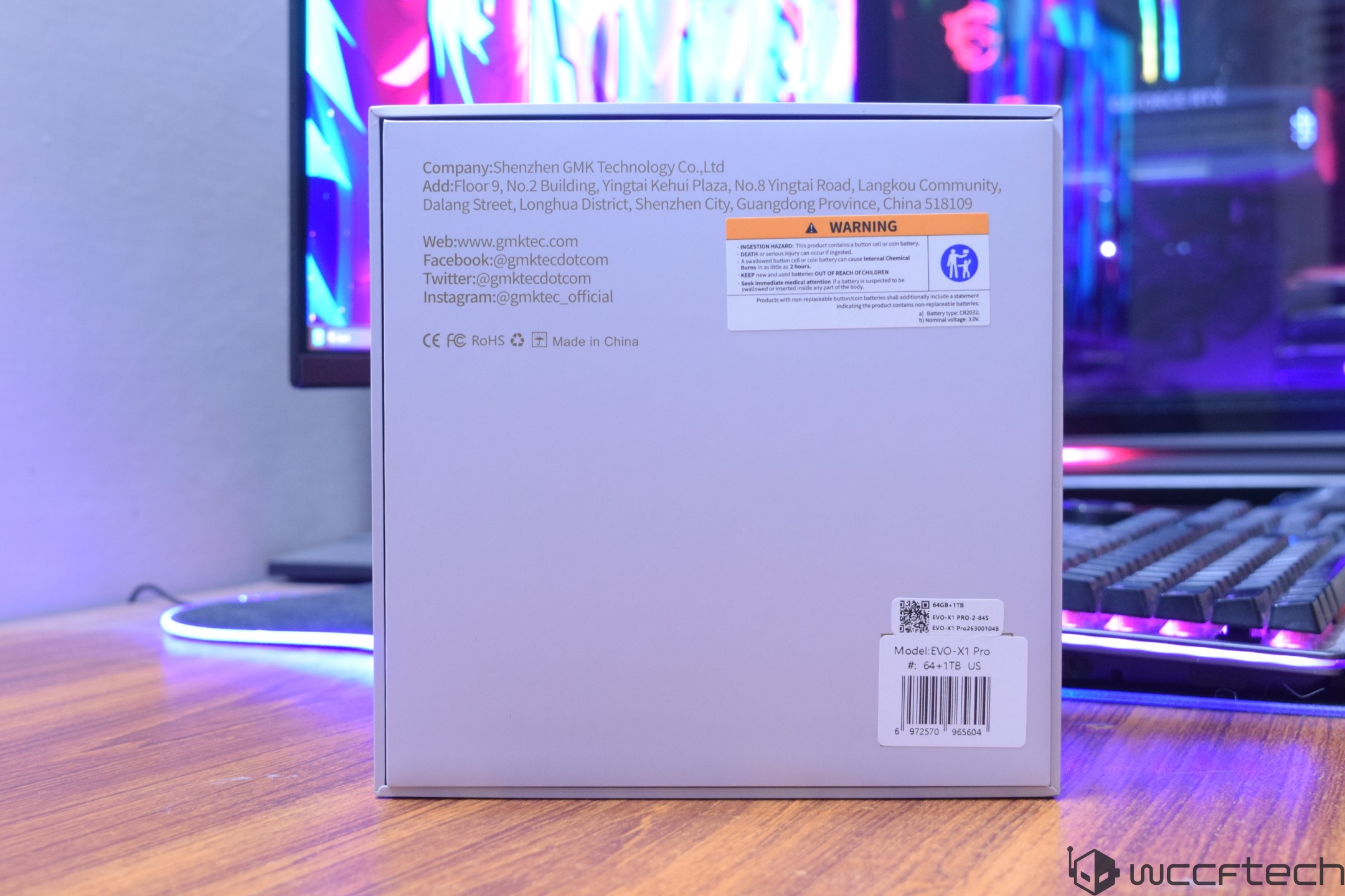 The back of a product box for the GMK EVO-X1 Pro is displayed, showing company contact information and a warning label about battery safety, with a barcode sticker indicating the model as 'EVO-X1 Pro' and specification '64+1TB US.'