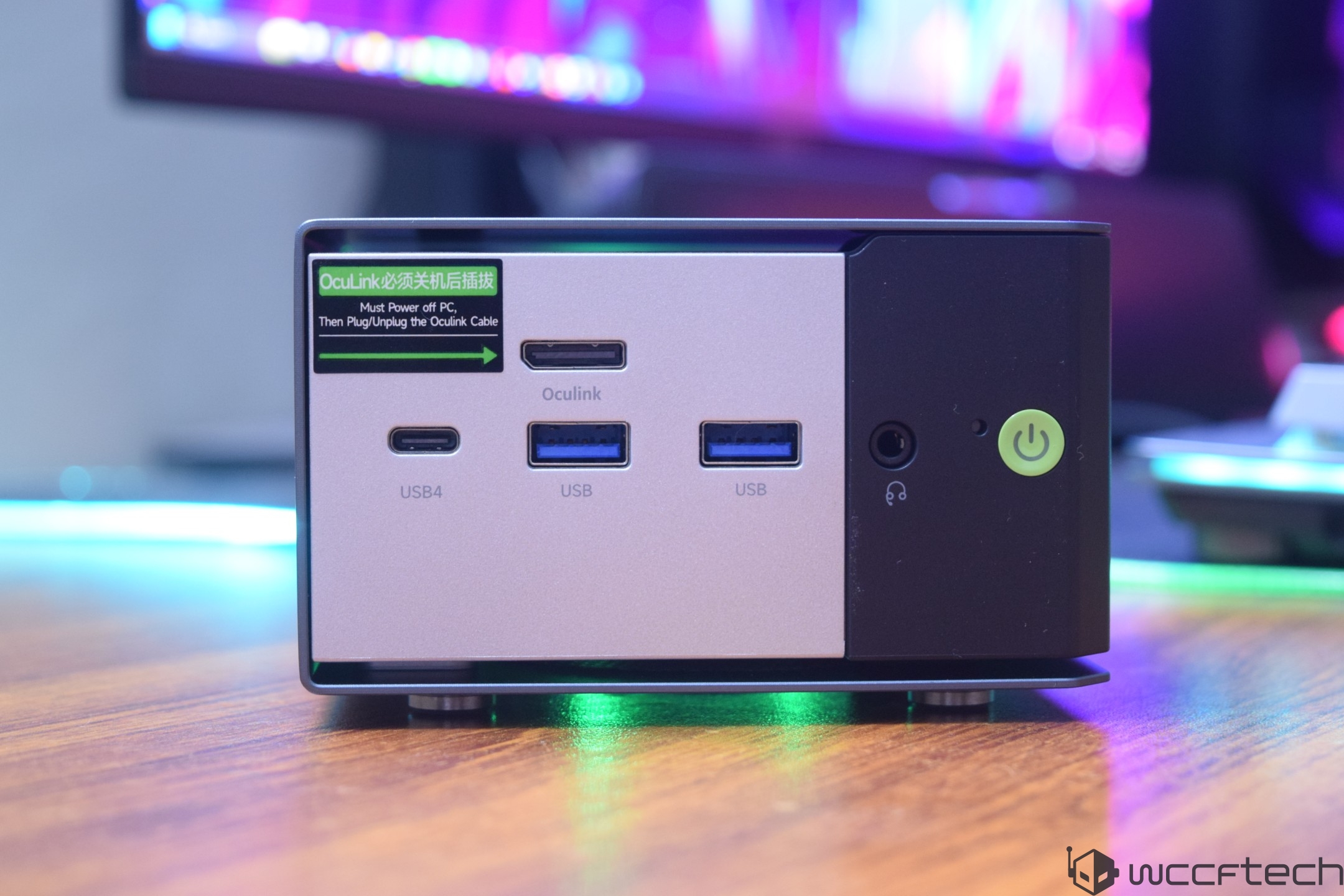 A compact PC with a front panel featuring two USB ports, one USB4 port, an Oculink port, a headphone jack, and a power button, with a label stating 'Must Power off PC, Then Plug/Unplug the Oculink Cable'.