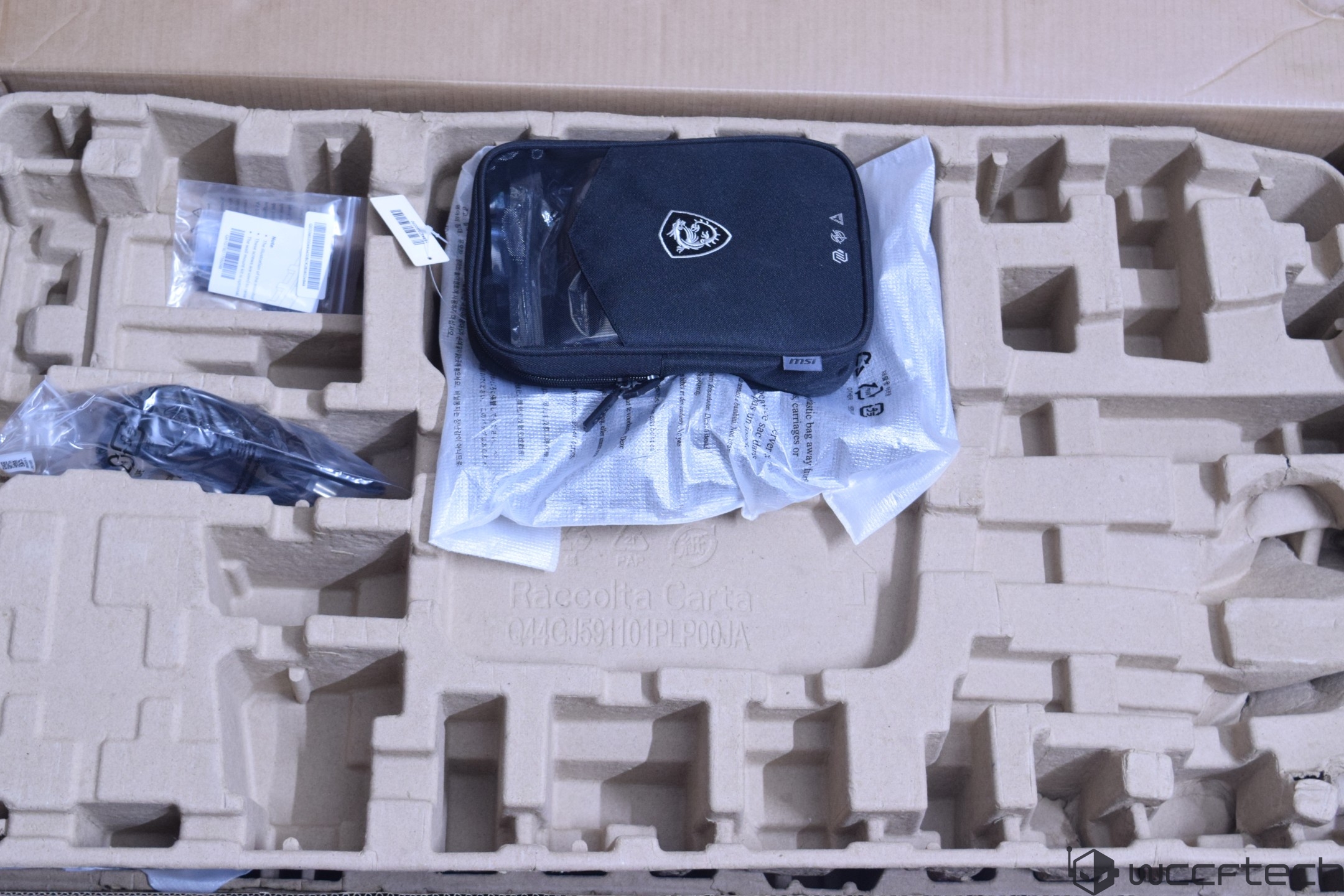 An MSI accessory kit is placed inside a large cardboard packaging with compartments, including a pouch displaying the MSI logo.