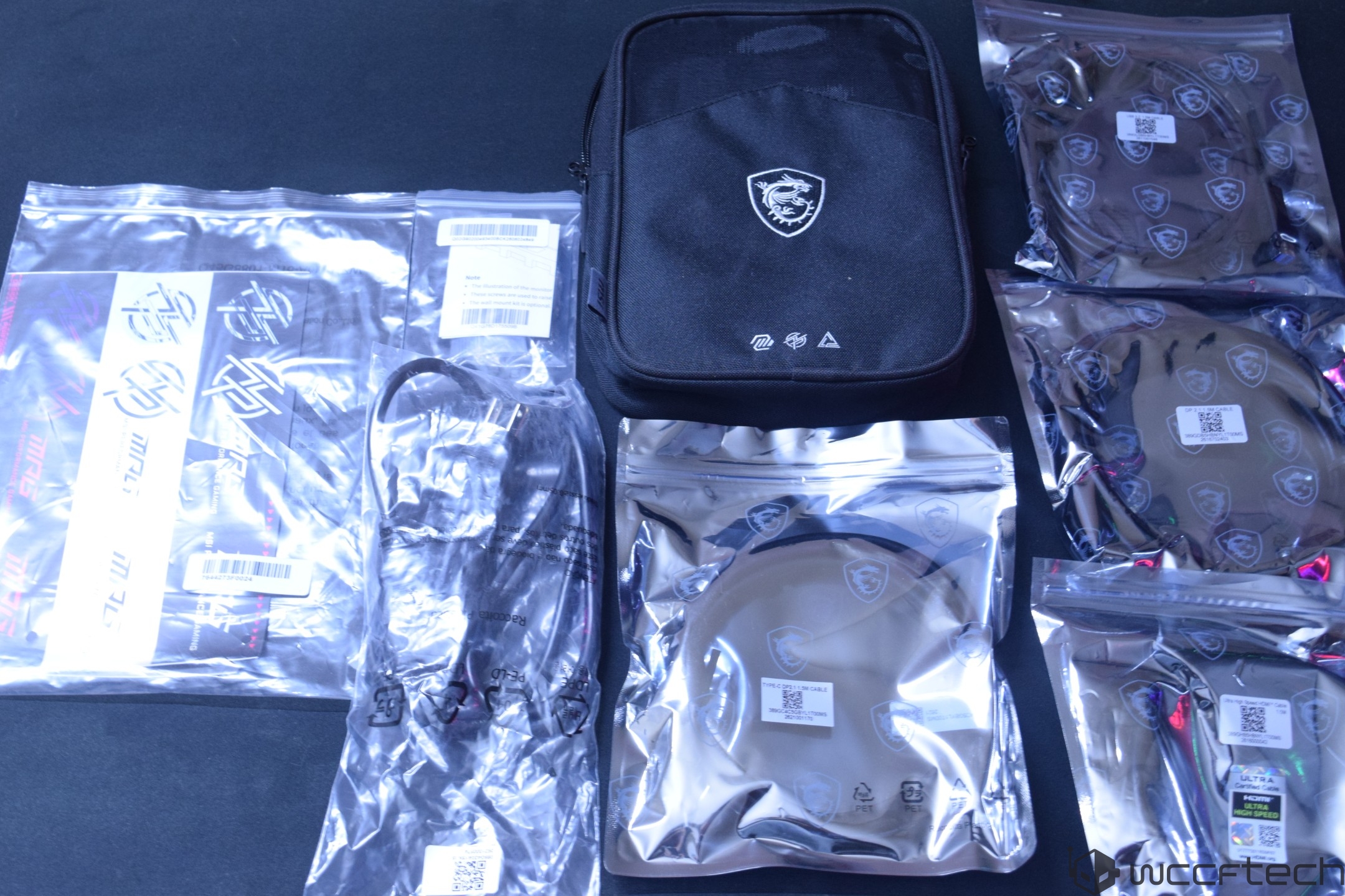 A collection of MSI-branded cables and accessories in sealed packaging, including a black travel case with the MSI dragon logo.