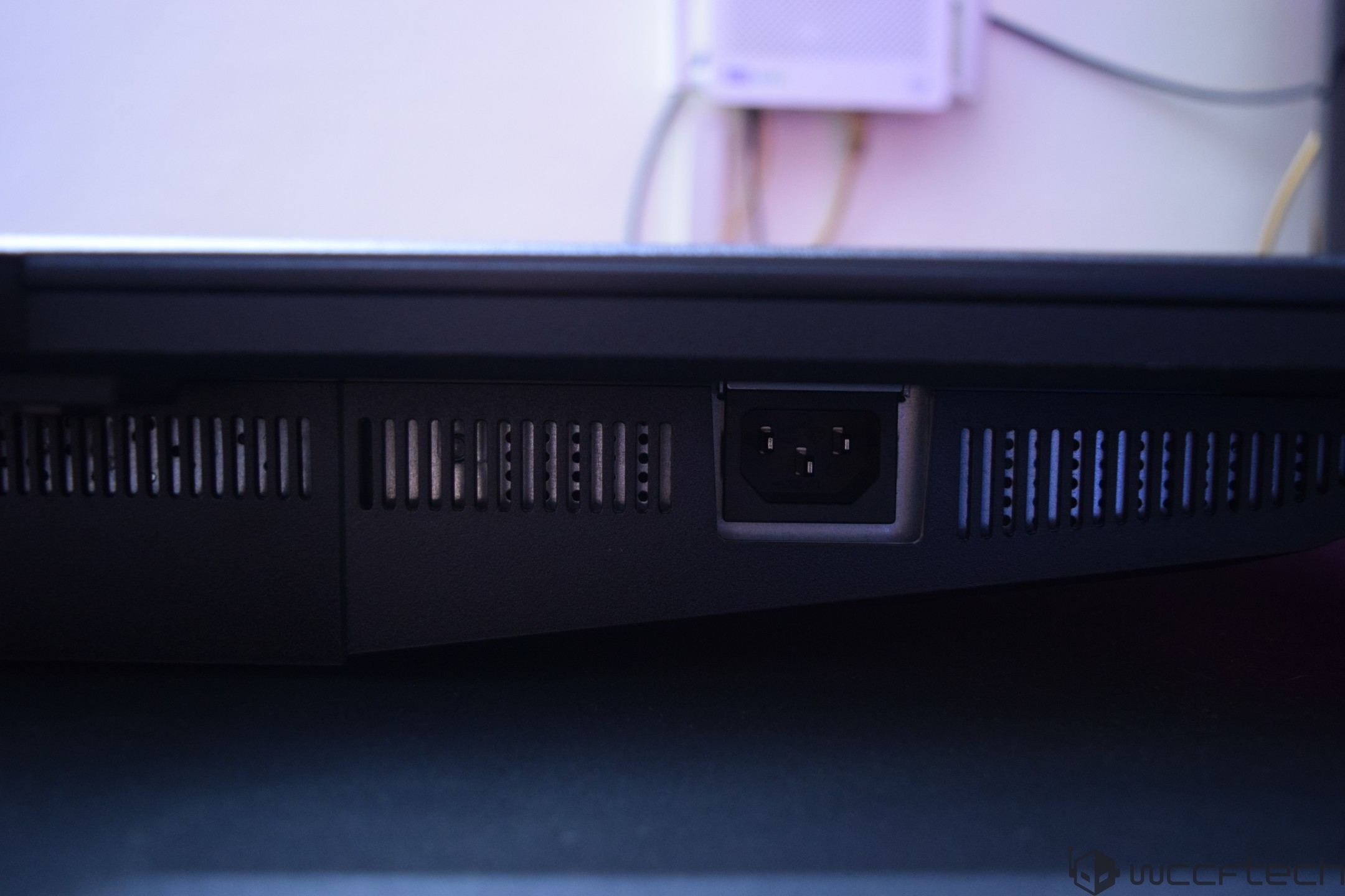 The back of an unbranded electronic device showing a power connector and ventilation grilles.