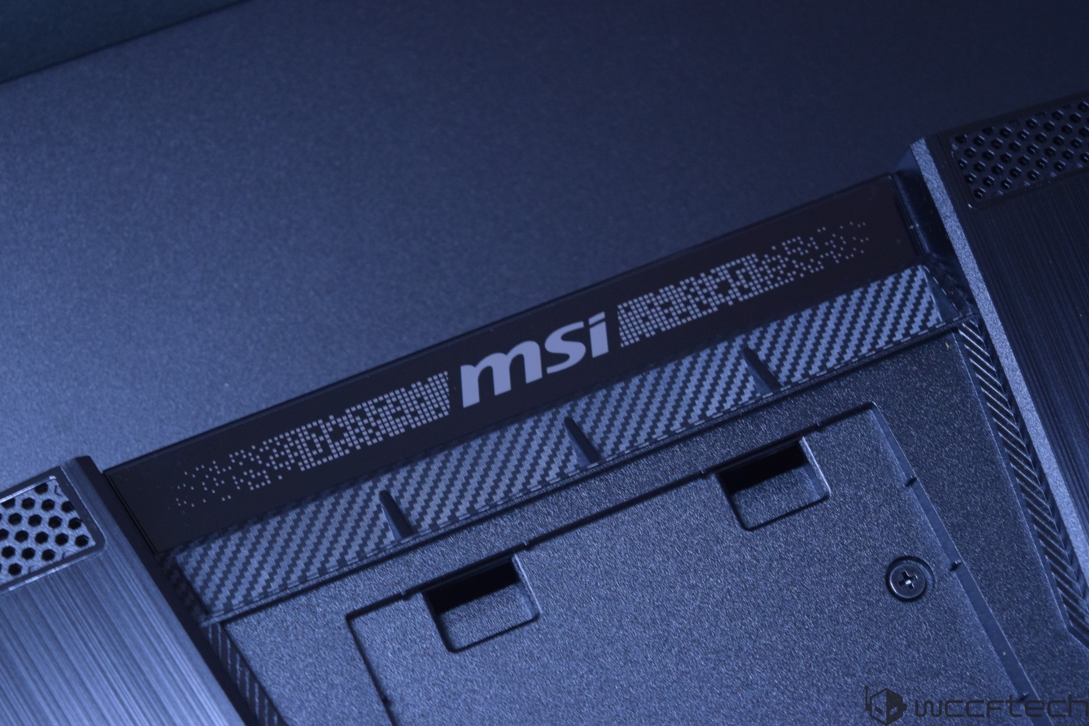 Close-up of an MSI logo on a carbon fiber-textured surface of electronic hardware.