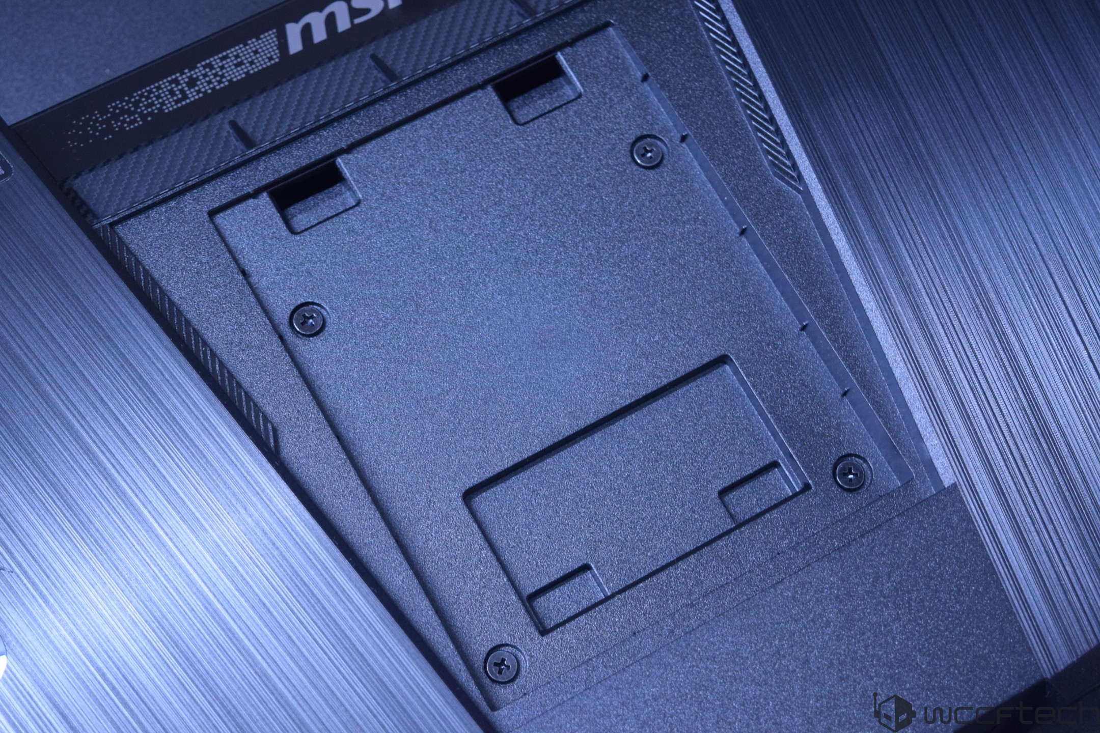 Close-up of an MSI laptop's bottom panel with a removable cover for accessing internal components.
